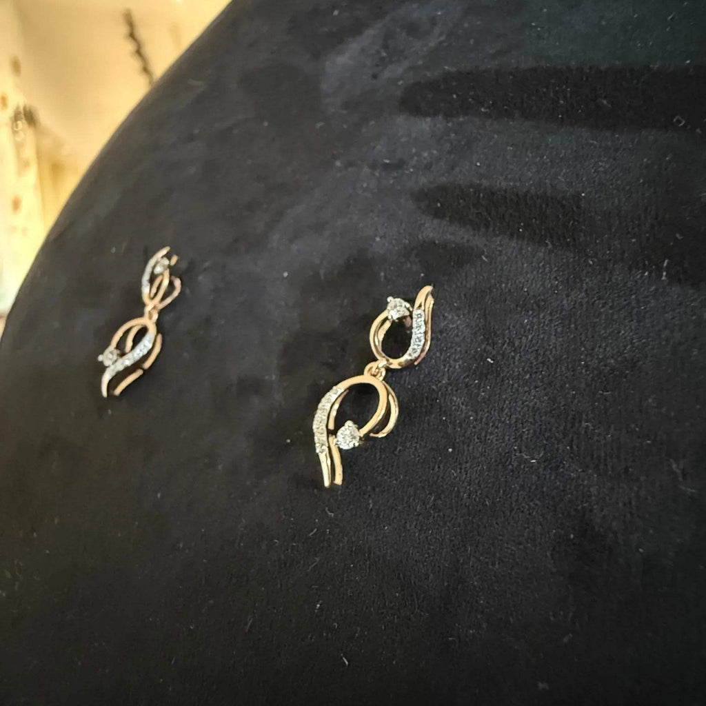 A gold diamond necklace with a chain link design, displayed on a mannequin bust, accompanied by a pair of matching earrings with a geometric design.