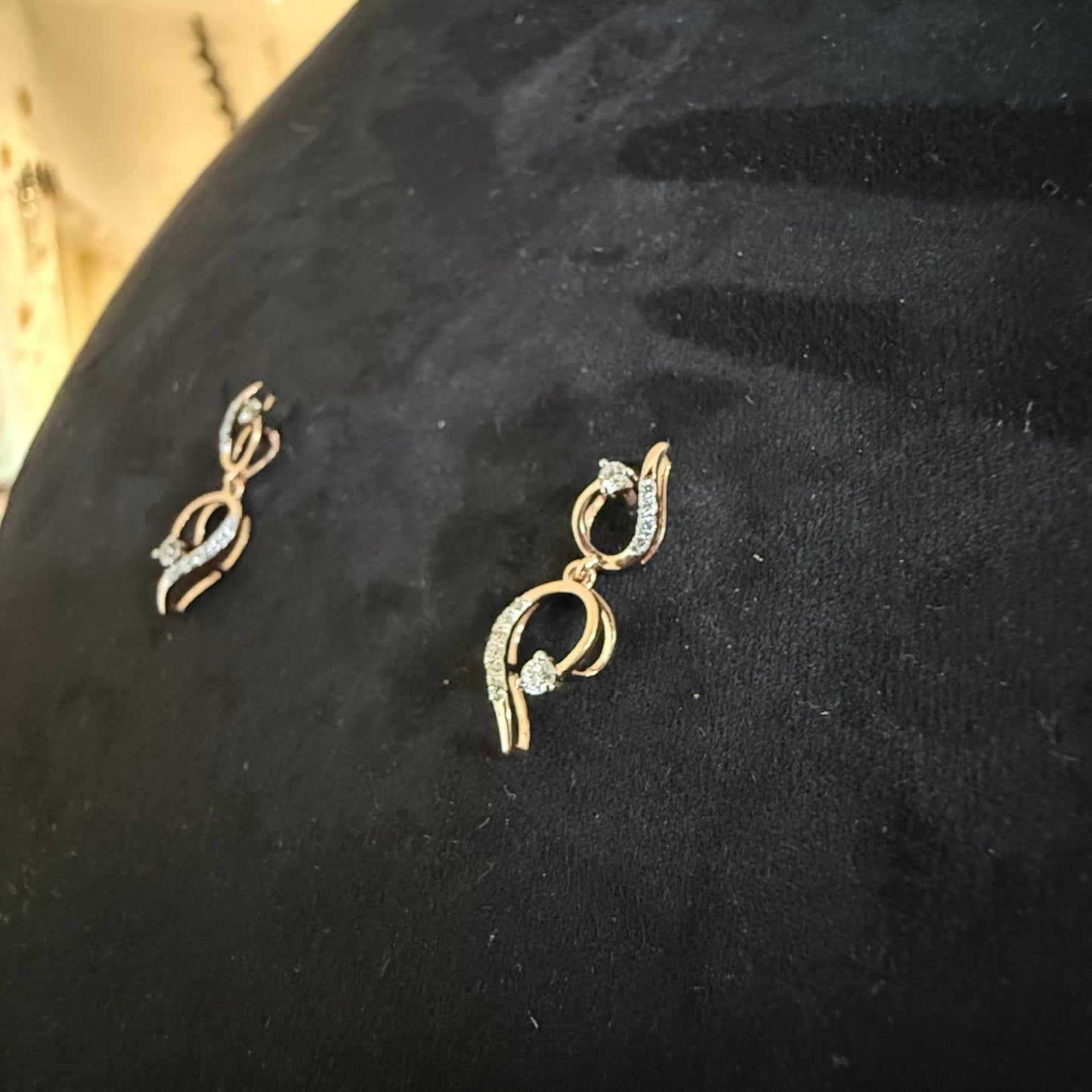 A gold diamond necklace with a chain link design, displayed on a mannequin bust, accompanied by a pair of matching earrings with a geometric design.