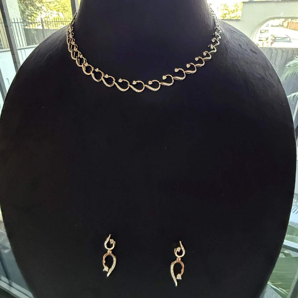 A gold diamond necklace with a chain link design, displayed on a mannequin bust, accompanied by a pair of matching earrings with a geometric design.