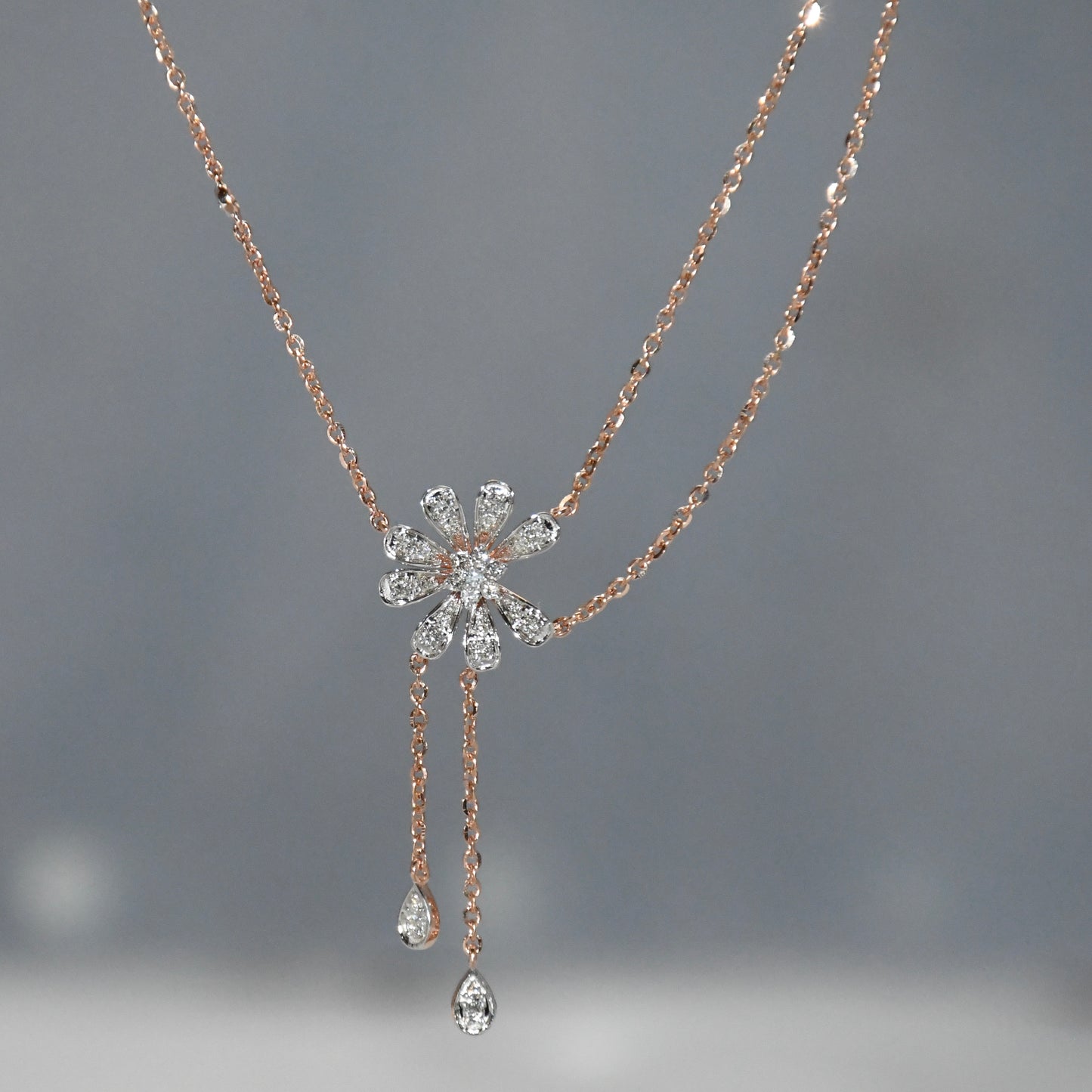 Rose gold necklace with a diamond pendant on a gray background