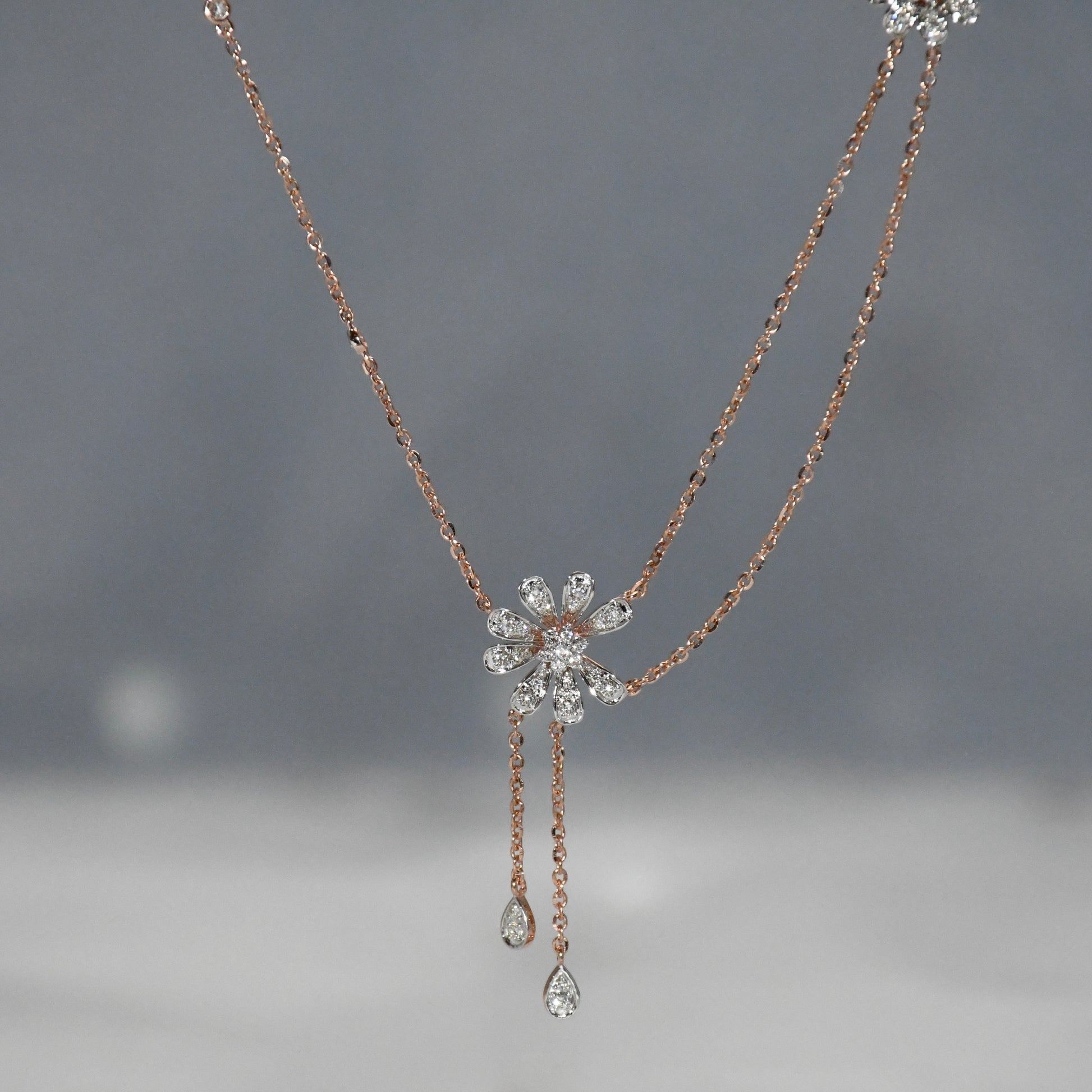 Delicate necklace with floral design and teardrop pendants on a gray background