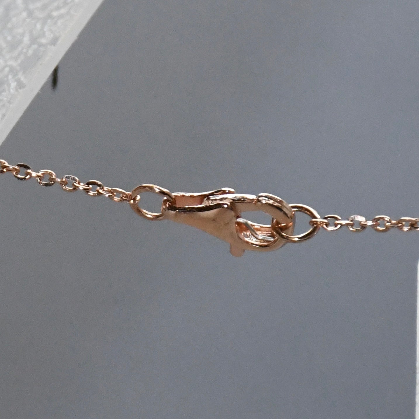 Rose gold clasp on a light gray background