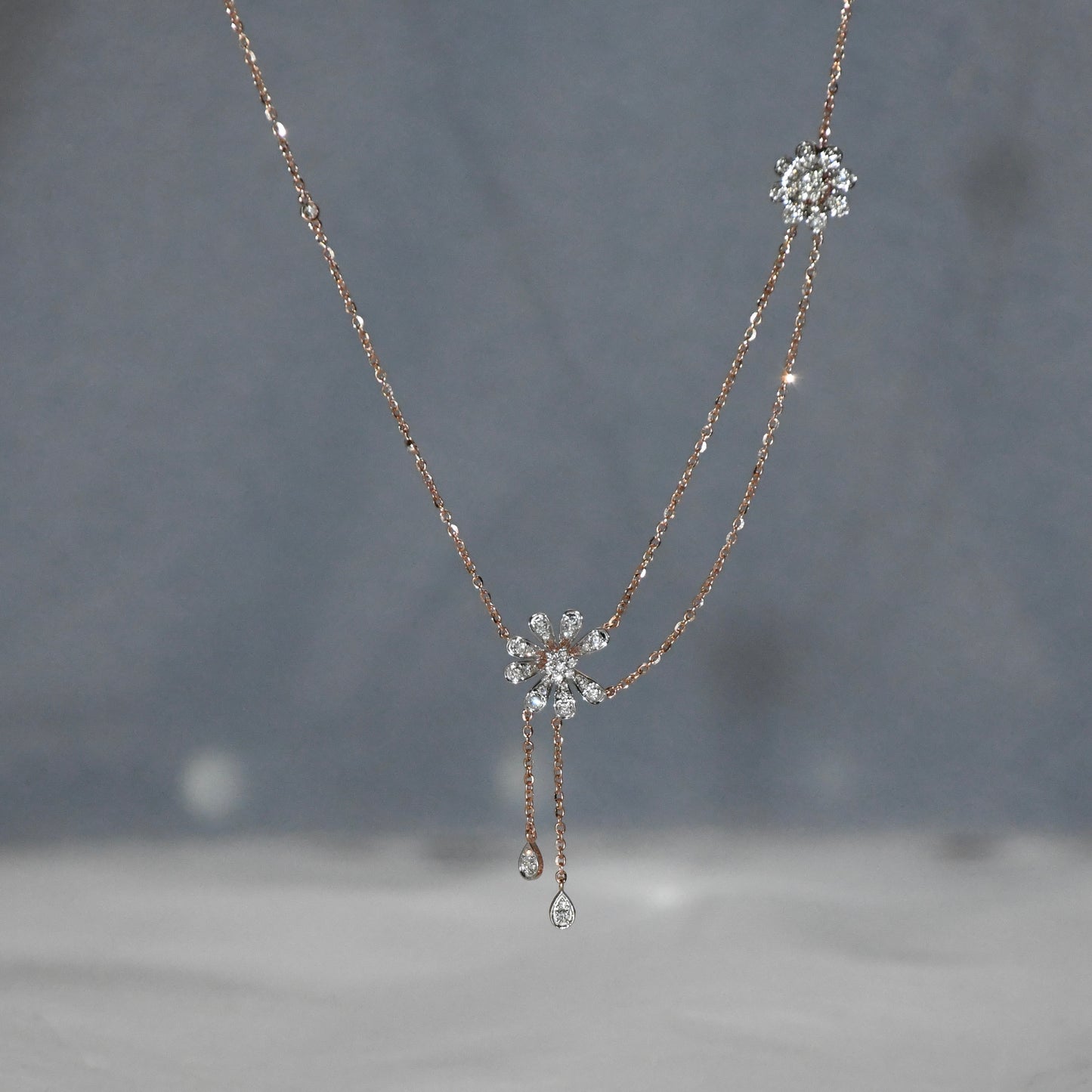 Delicate gold necklace with floral pendants on a blurred background
