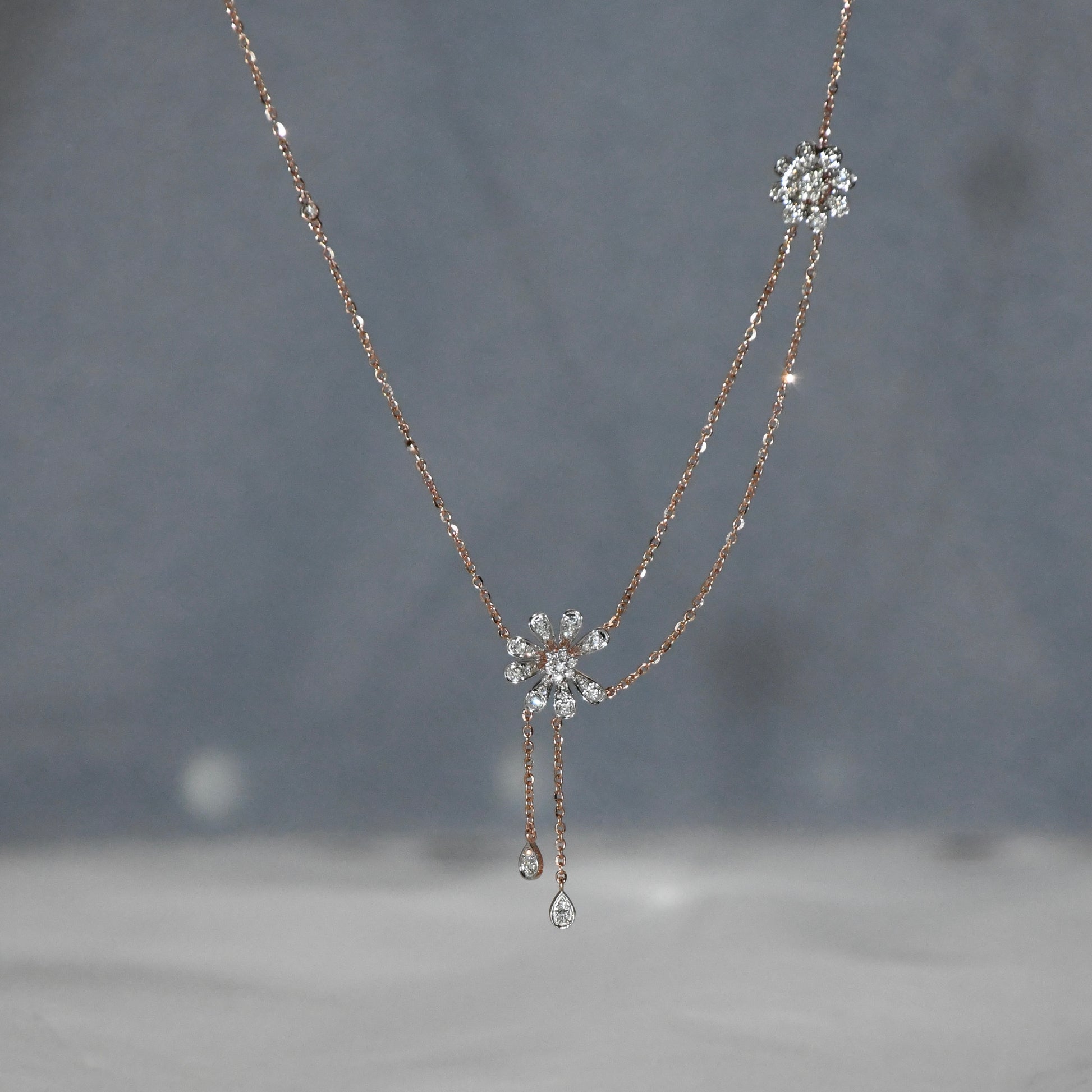 Delicate gold necklace with floral pendants on a blurred background