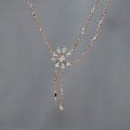 Rose gold necklace with a floral pendant on a gray background