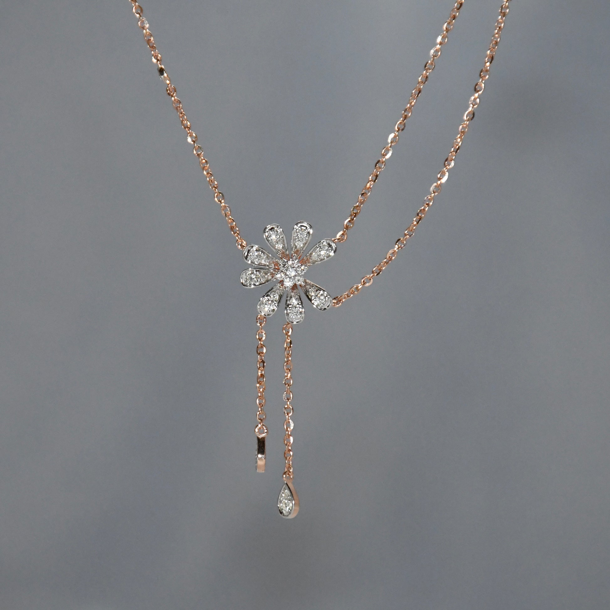Rose gold necklace with a floral pendant on a gray background