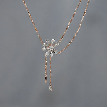 Rose gold necklace with a floral pendant on a gray background