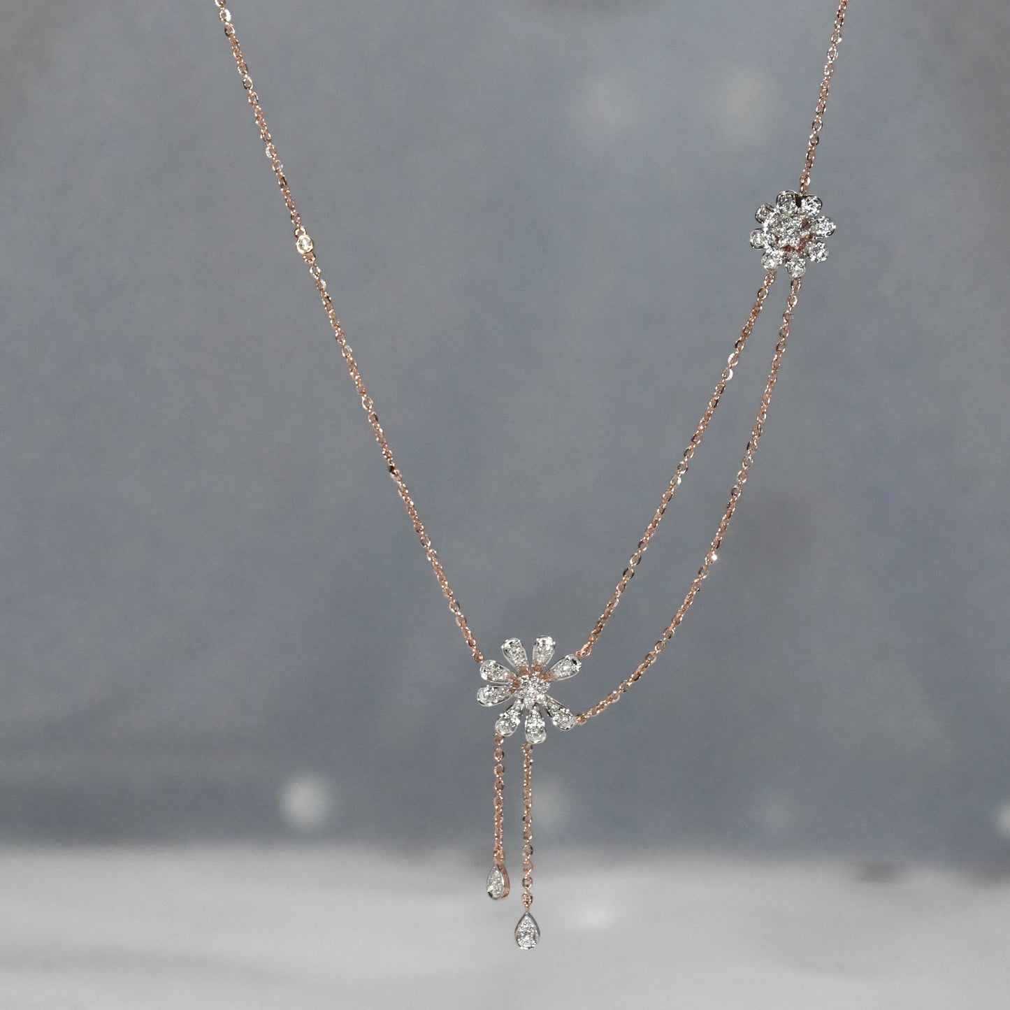 Delicate diamond necklace with floral pendants on a gray background