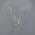 Rose gold necklace with diamond accents on a gray background