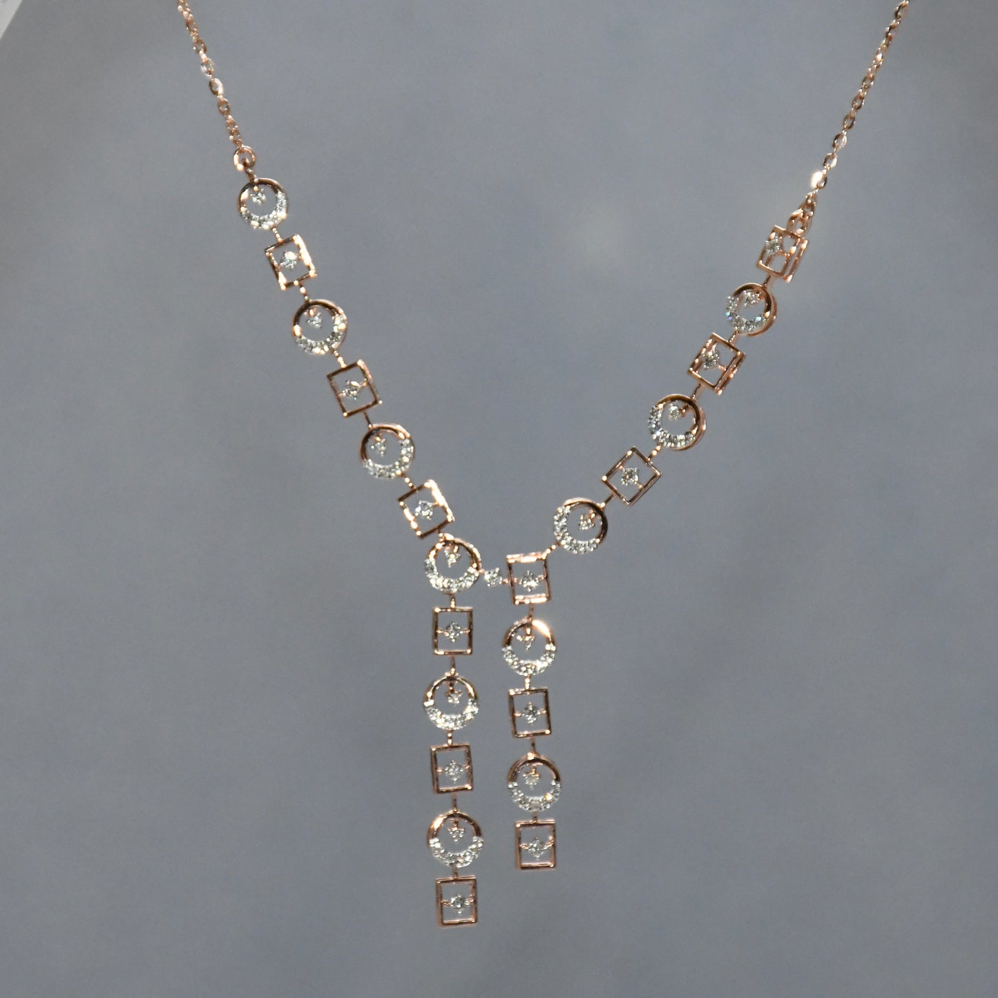 Rose gold necklace with diamond accents on a gray background