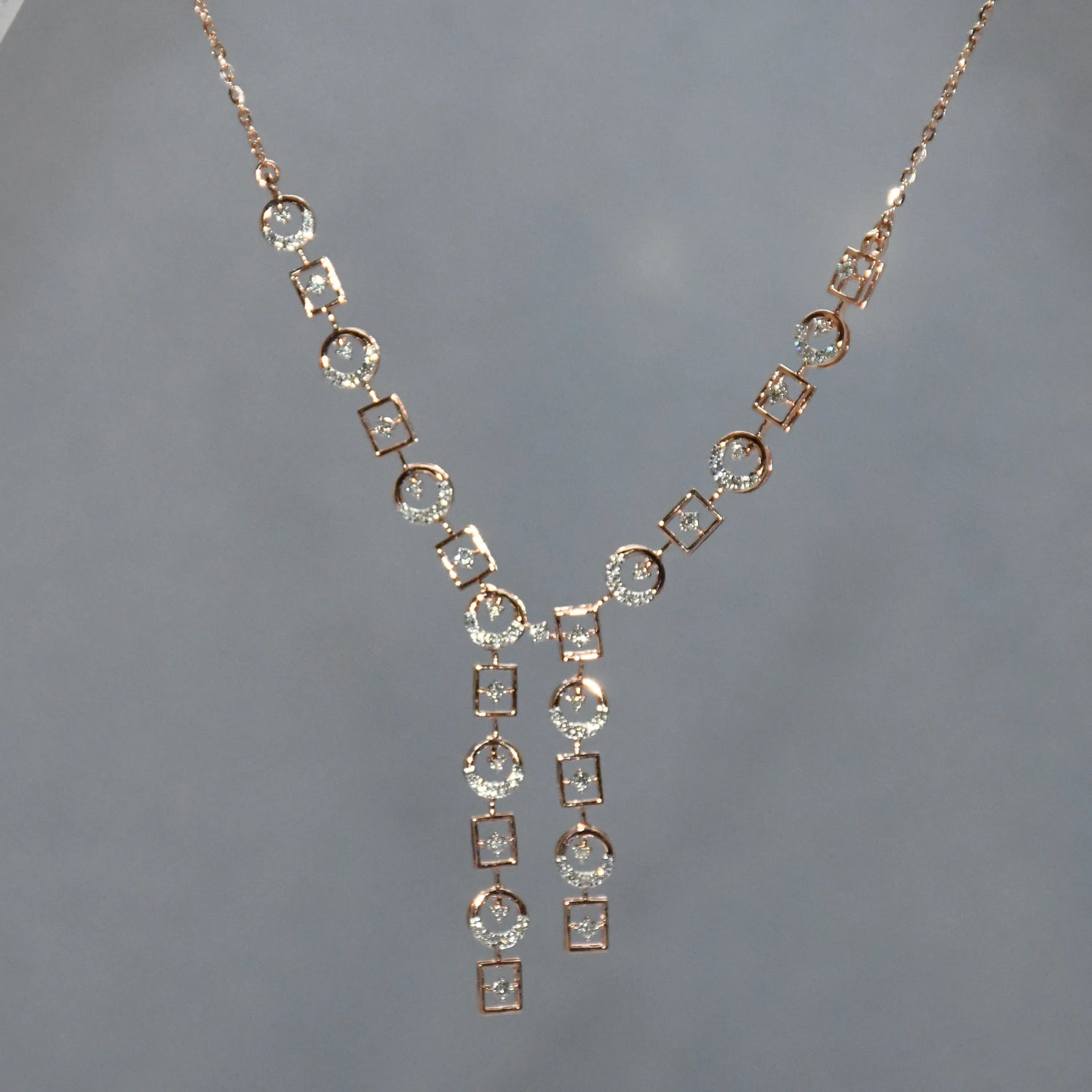 Rose gold necklace with diamond accents on a gray background