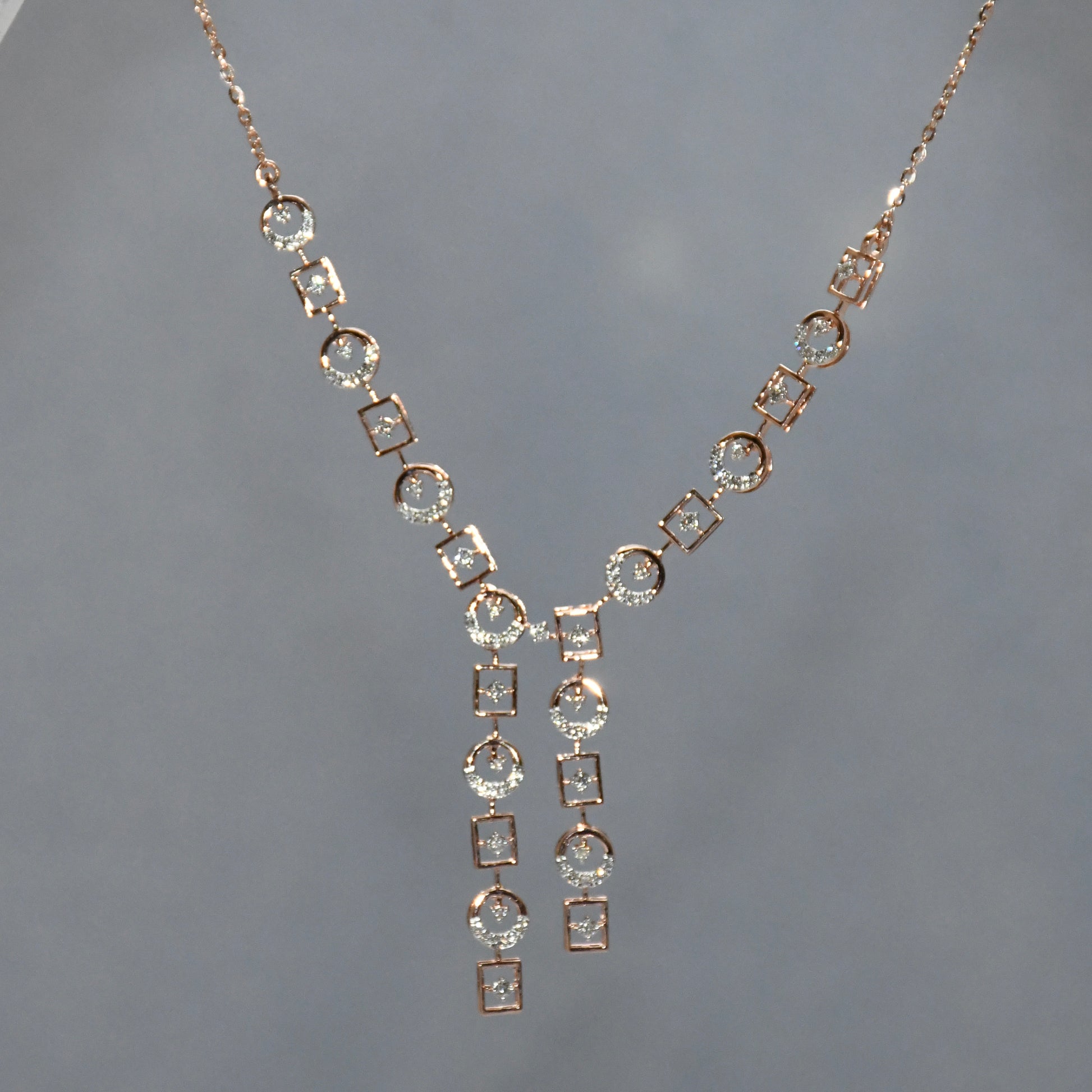 Rose gold necklace with diamond accents on a gray background