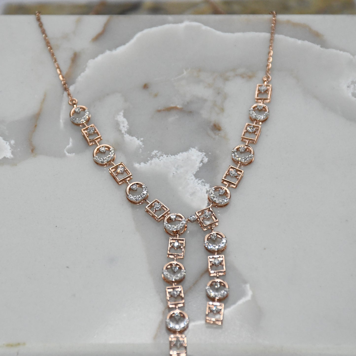 Rose gold necklace with diamonds on a marble surface