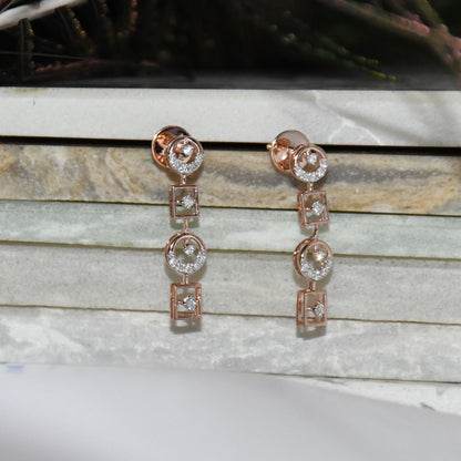 Rose gold earrings with diamond accents on a marble surface