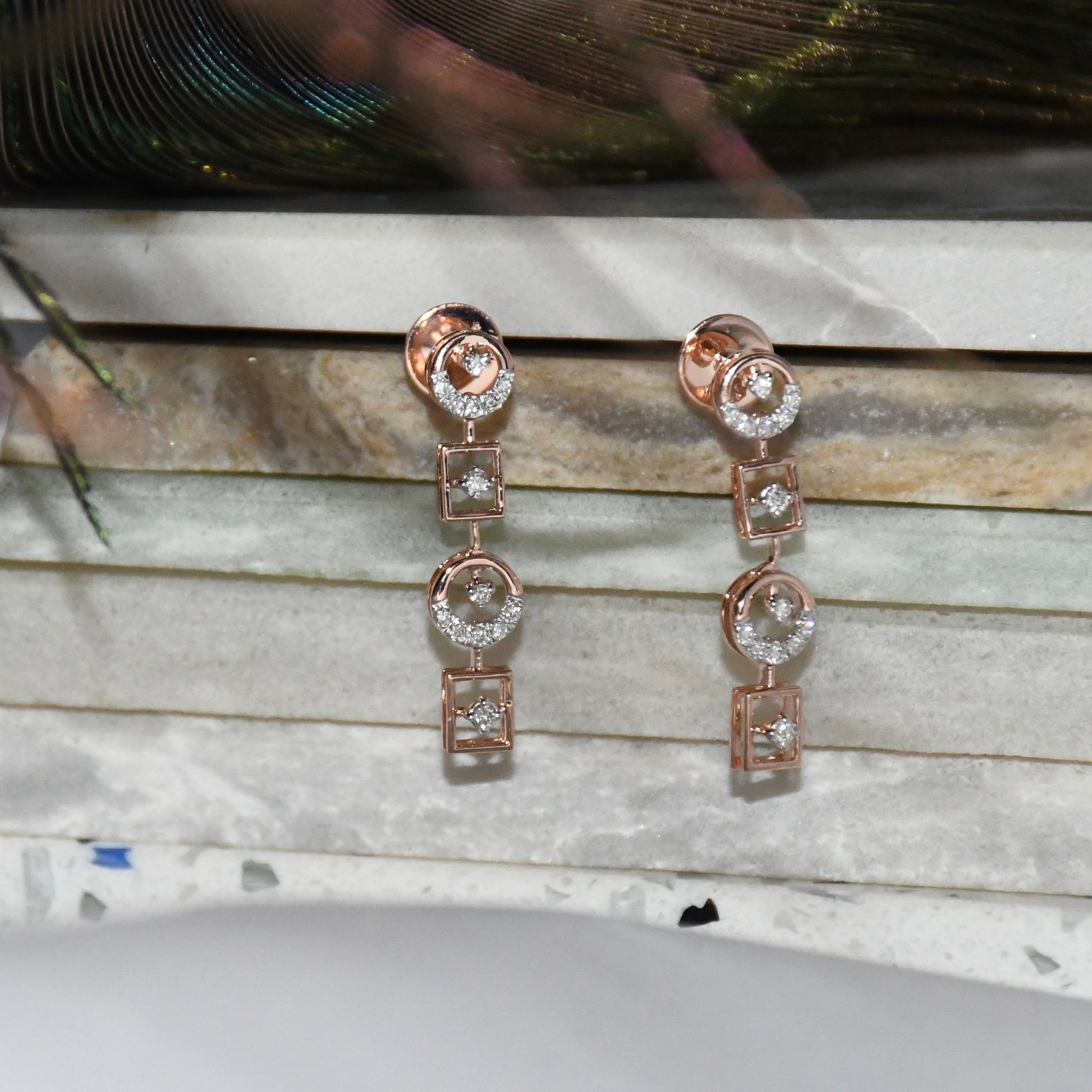Rose gold earrings with clear diamonds on a marble surface