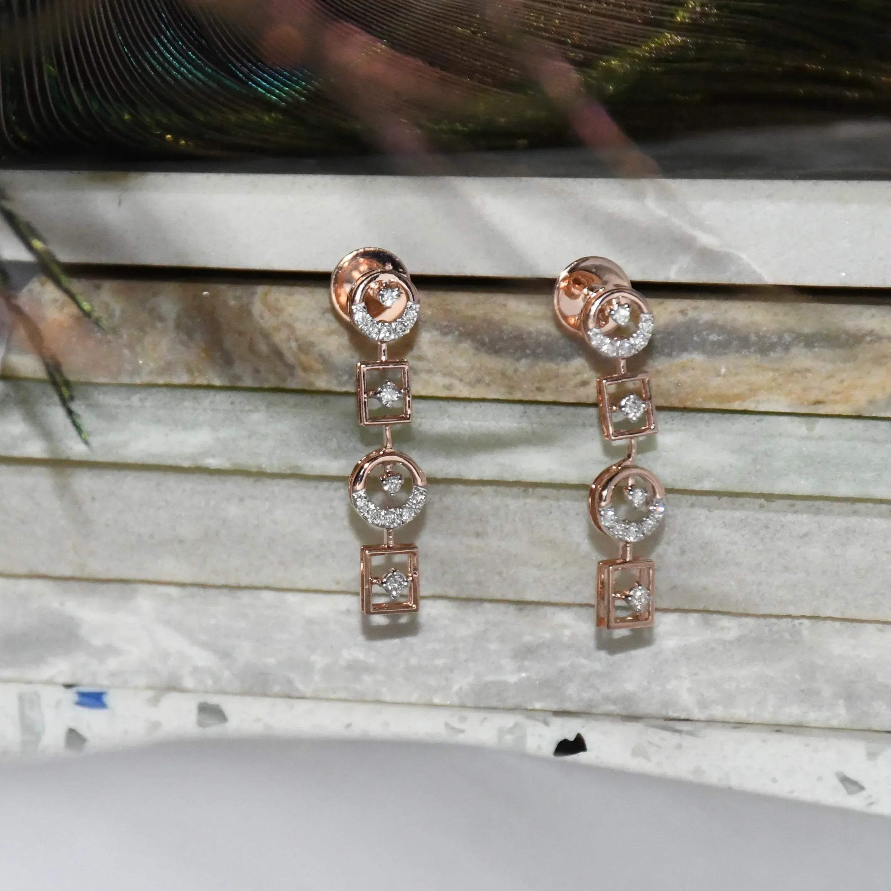 Rose gold earrings with clear diamonds on a marble surface