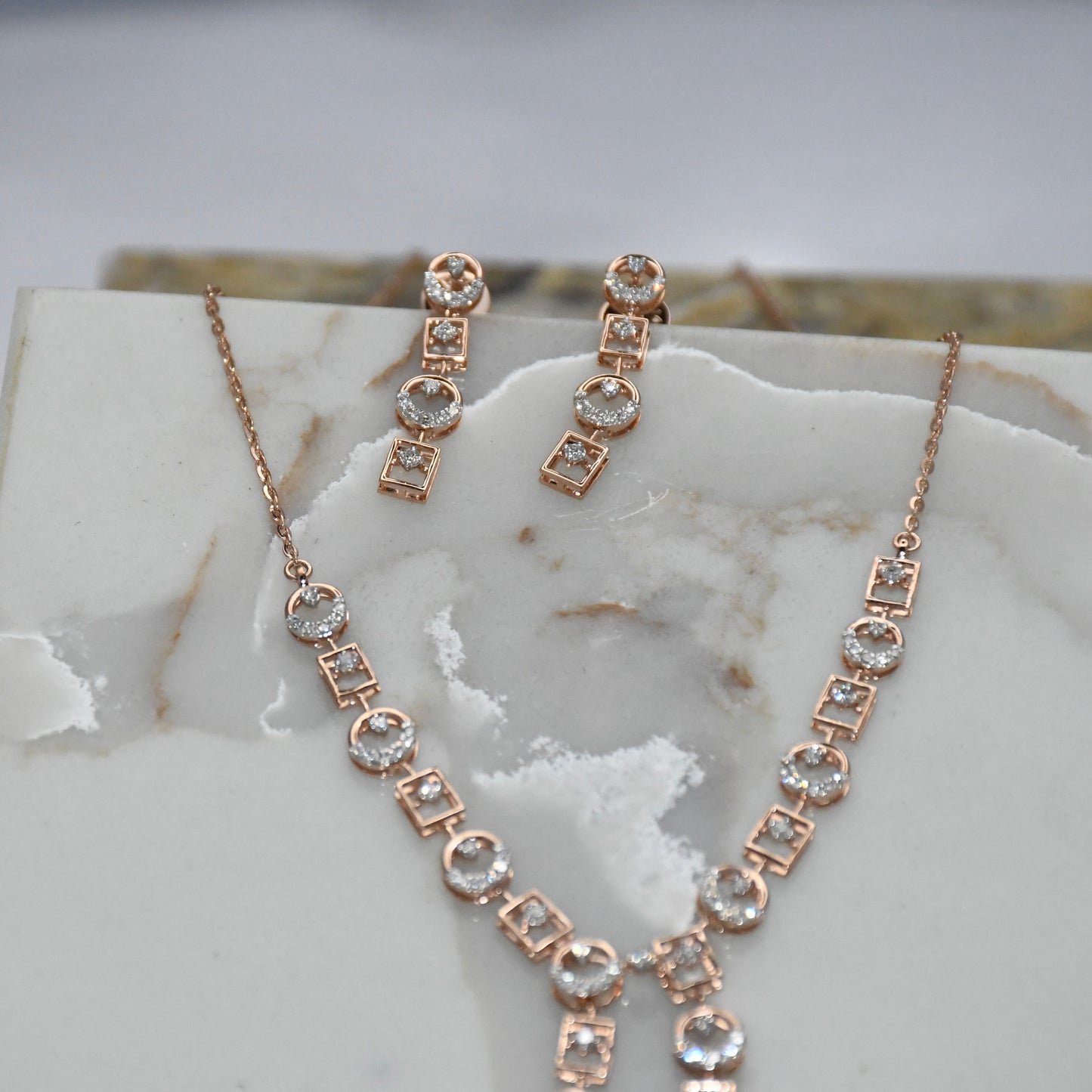 Rose gold necklace and earrings on a marble surface