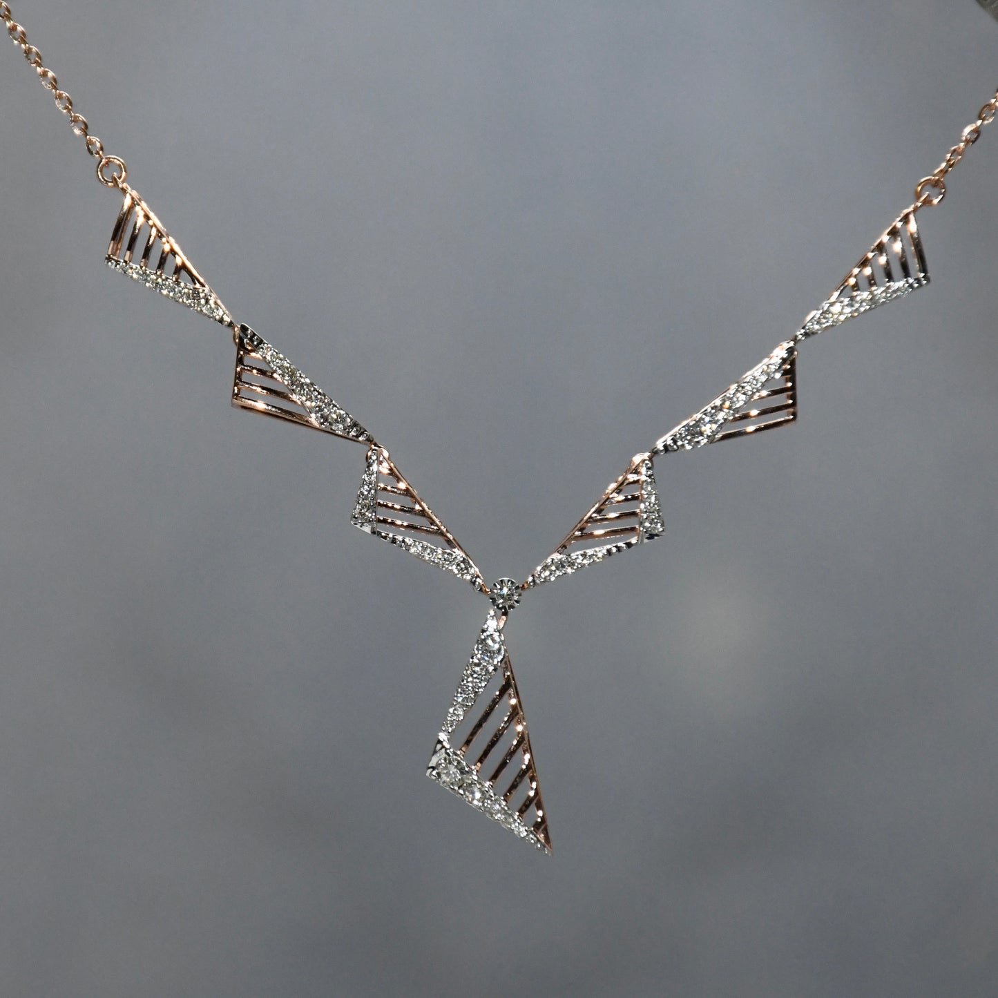 diamond necklace with geometric triangle design on a gray background