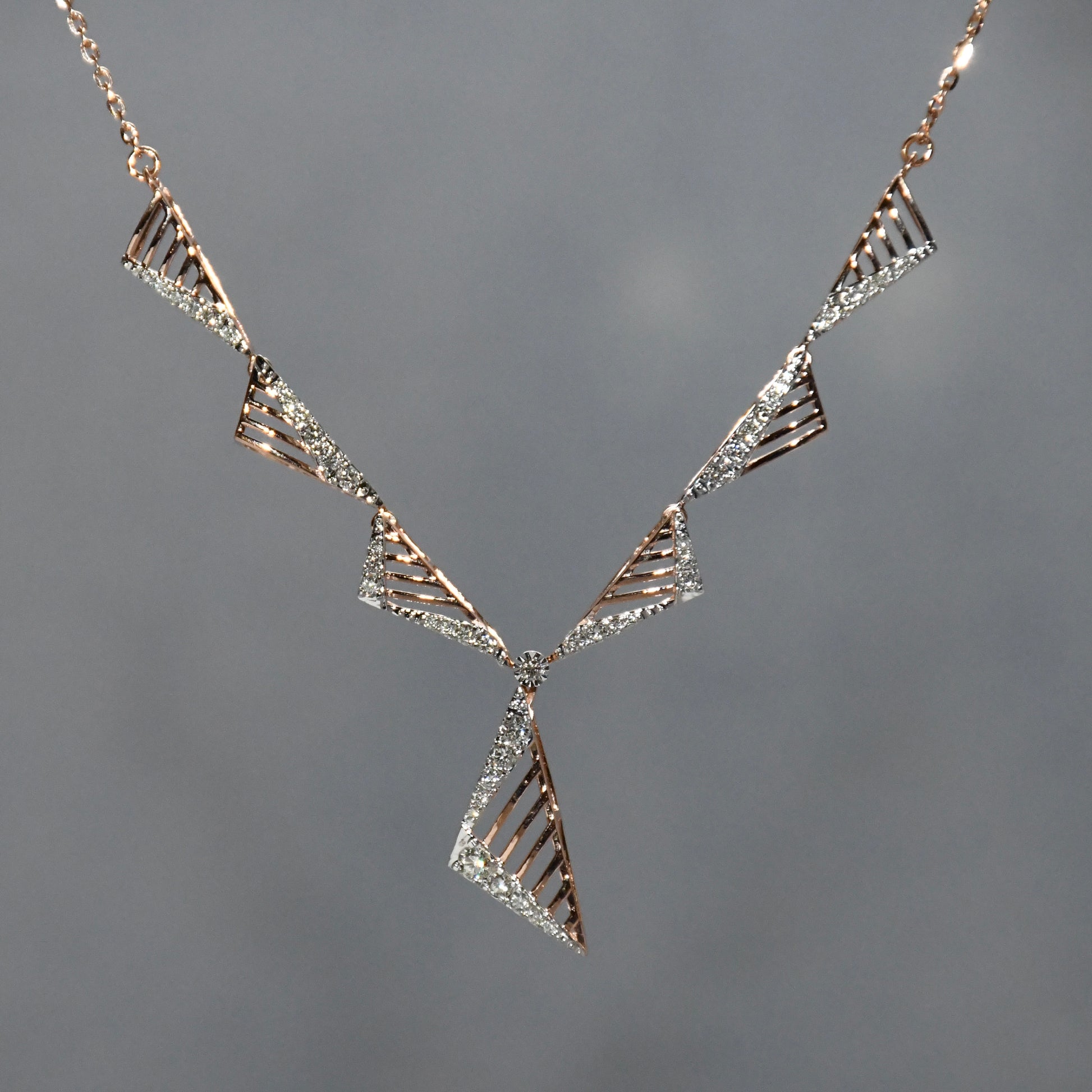 Geometric diamond necklace with triangular design on a gray background.