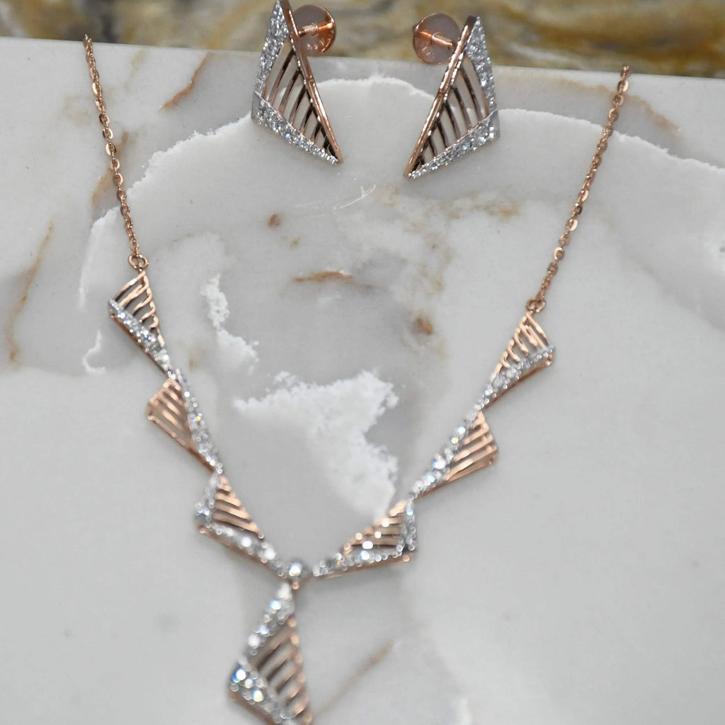 Gold diamond necklace and earrings on a marble surface.