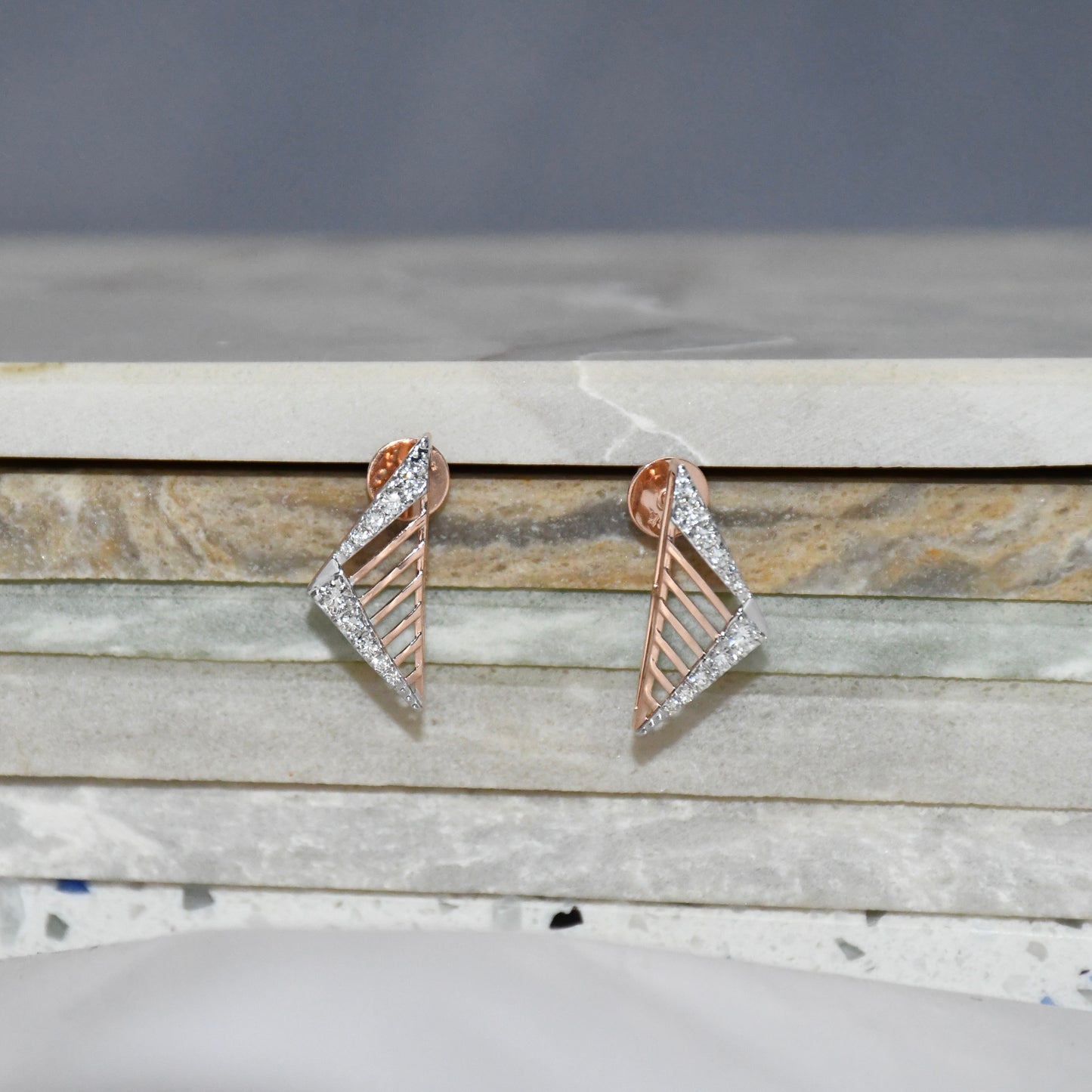 Pair of gold and diamond geometric earrings on a marble surface
