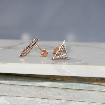 Rose gold earrings with diamond accents on a marble surface.