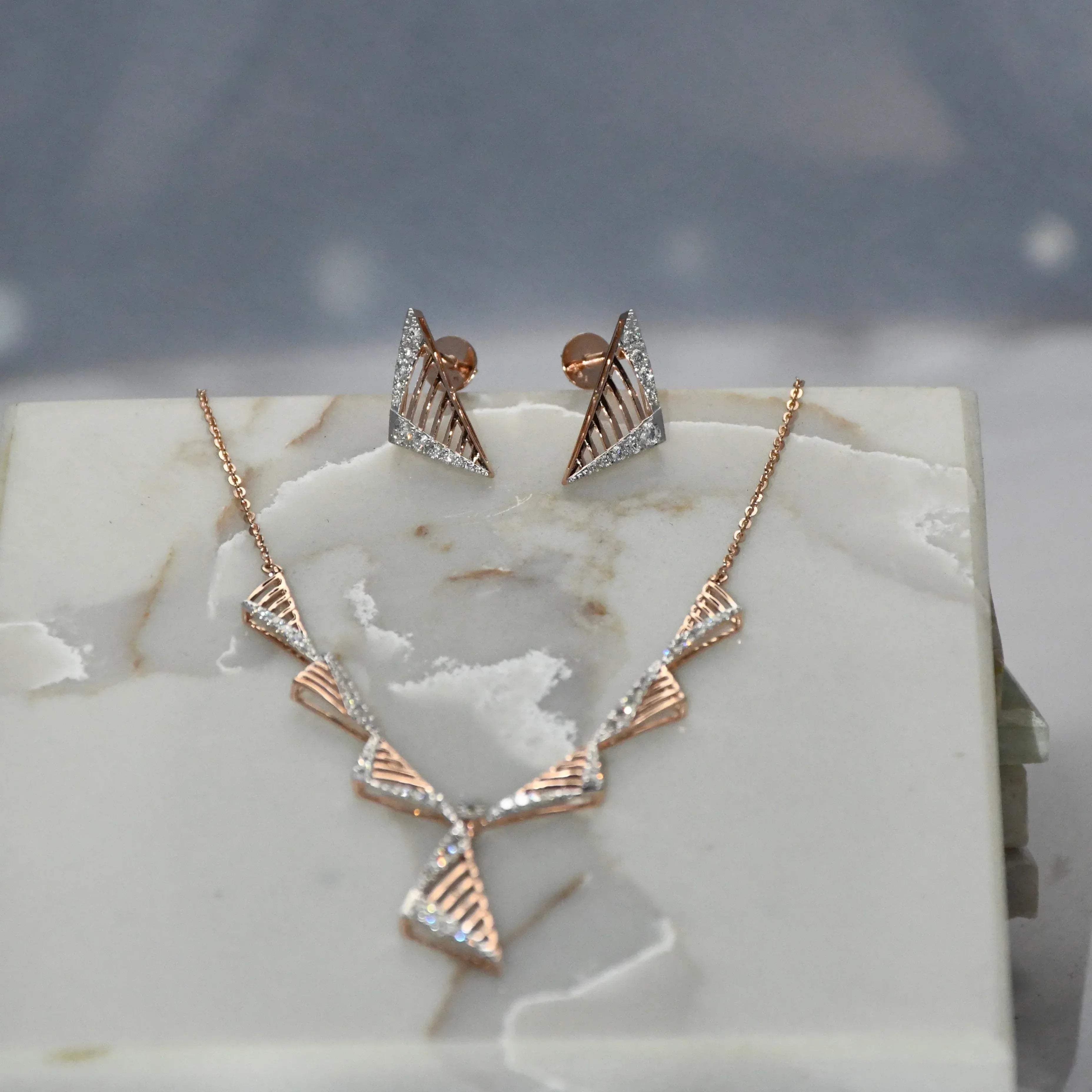 Gold diamond necklace and earrings on a marble surface