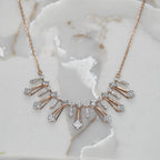 Rose gold necklace with diamond accents on a marble surface
