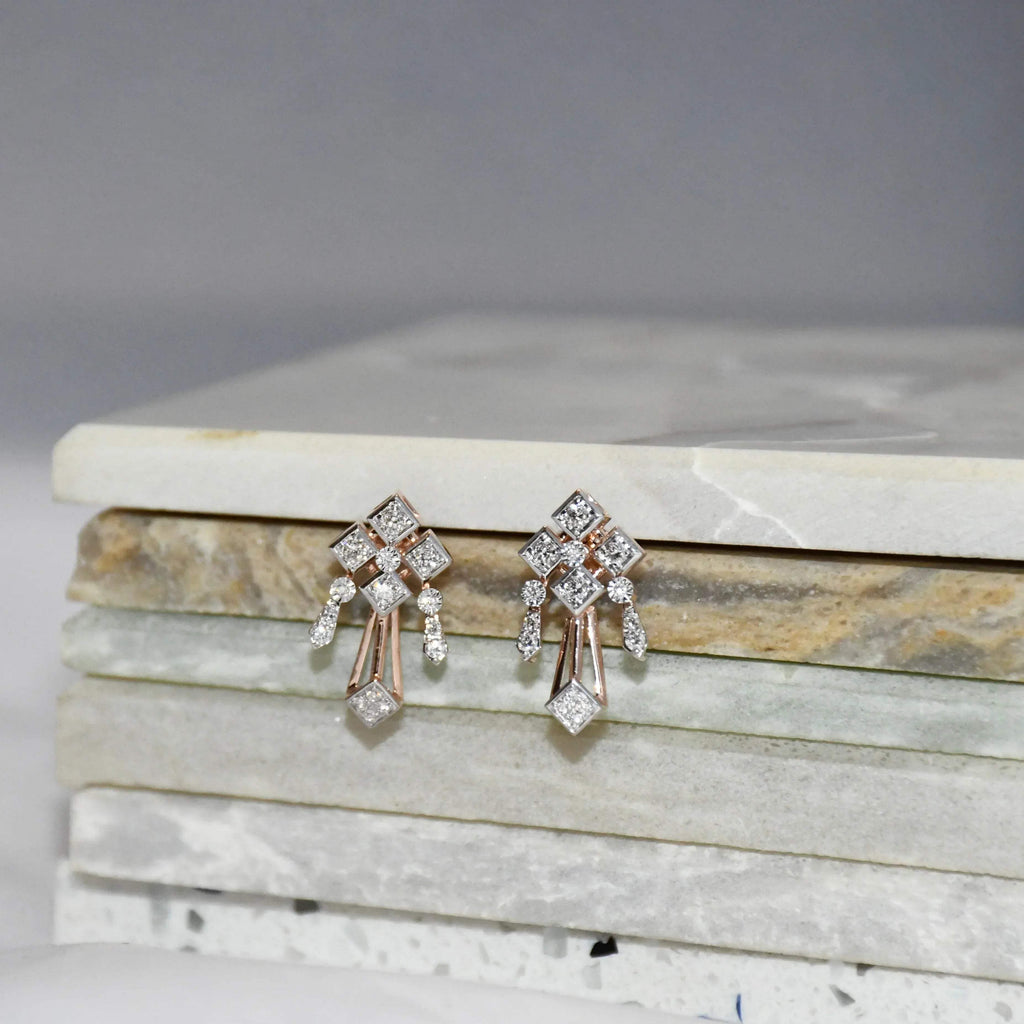 Pair of diamond earrings on a marble surface.