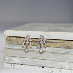 Pair of diamond earrings on a marble surface.