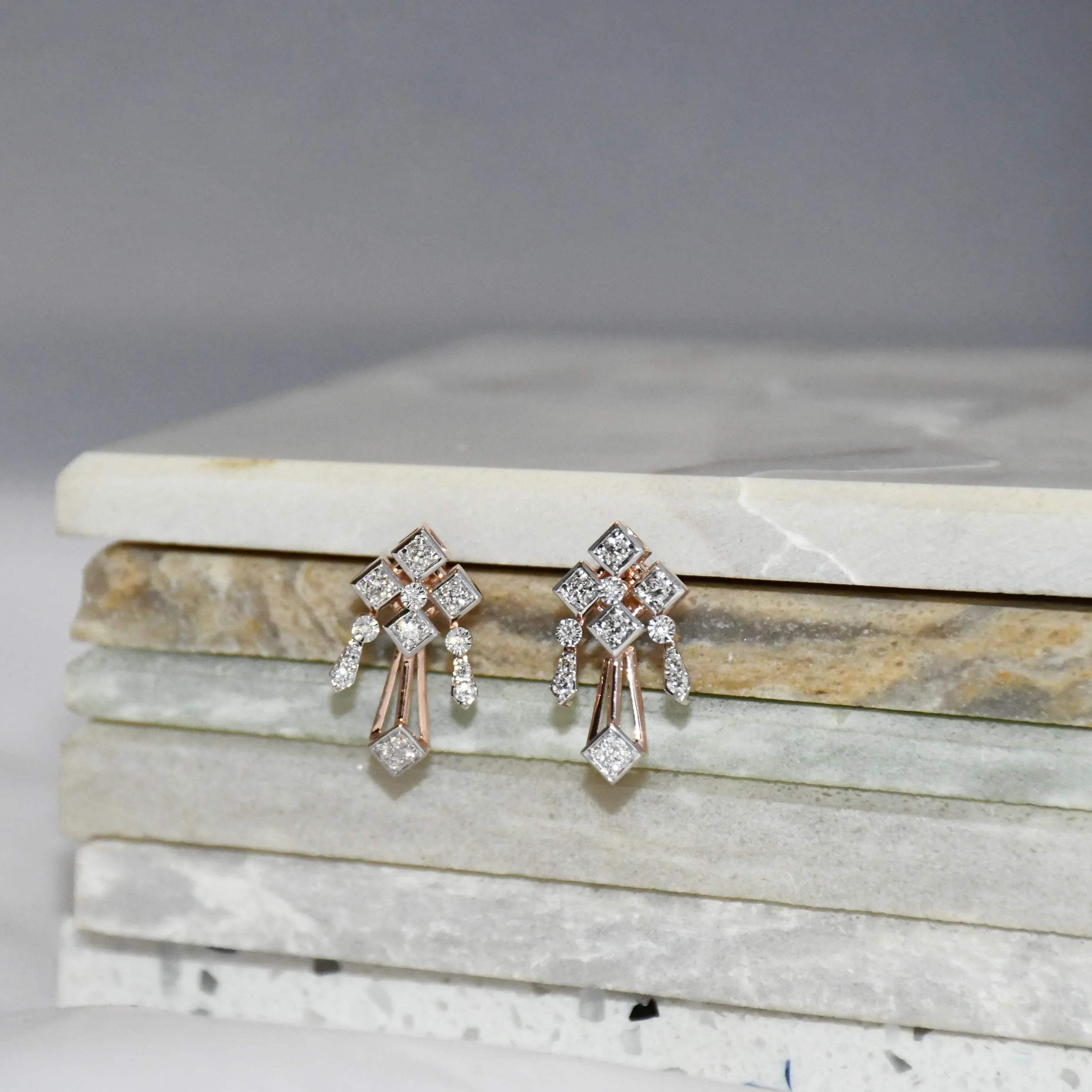 Pair of diamond earrings on a marble surface.
