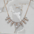 Rose gold necklace with diamond accents on a marble surface
