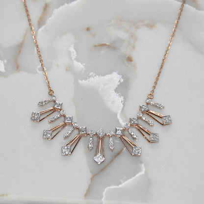 Rose gold necklace with diamond accents on a marble surface