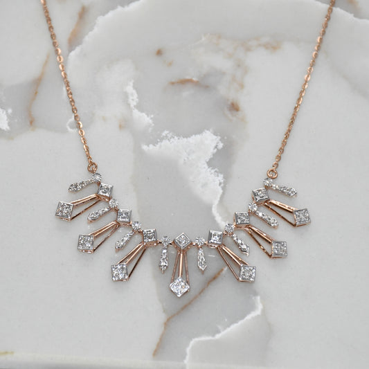 Rose gold necklace with diamond accents on a marble surface
