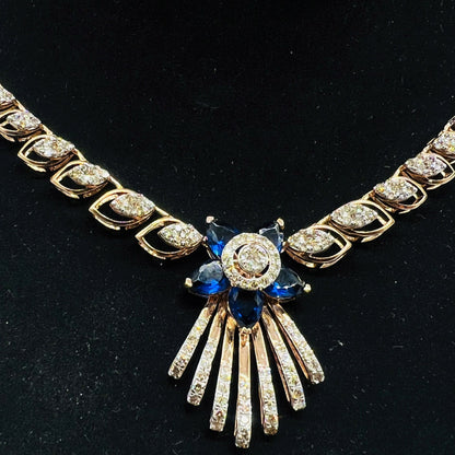 A gold wedding necklace with round-cut blue color stones and clear diamonds displayed on a mannequin bust.