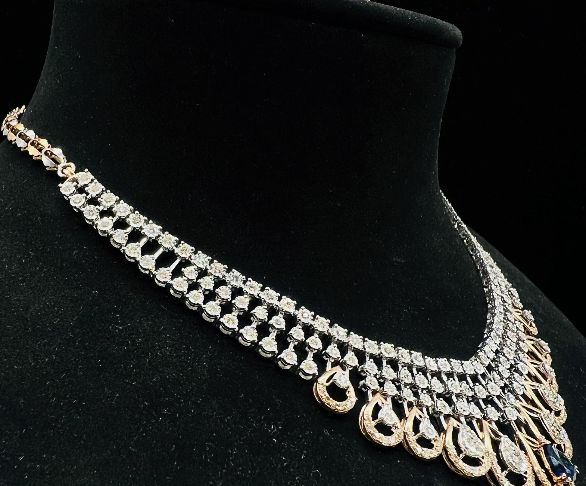 A gold bridal diamond necklace with round-cut beauty displayed on a mannequin bust.