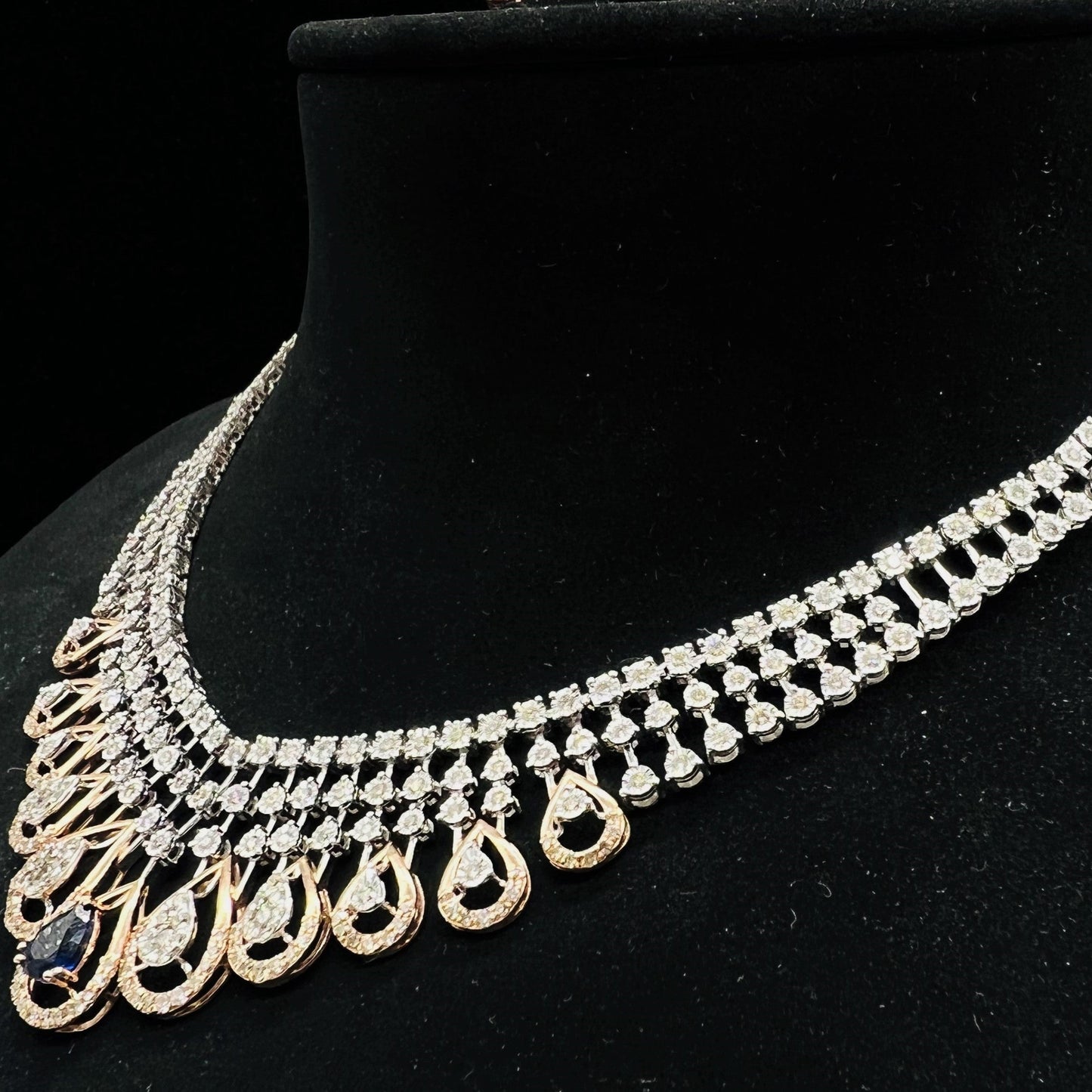 A gold bridal diamond necklace with round-cut beauty displayed on a mannequin bust.