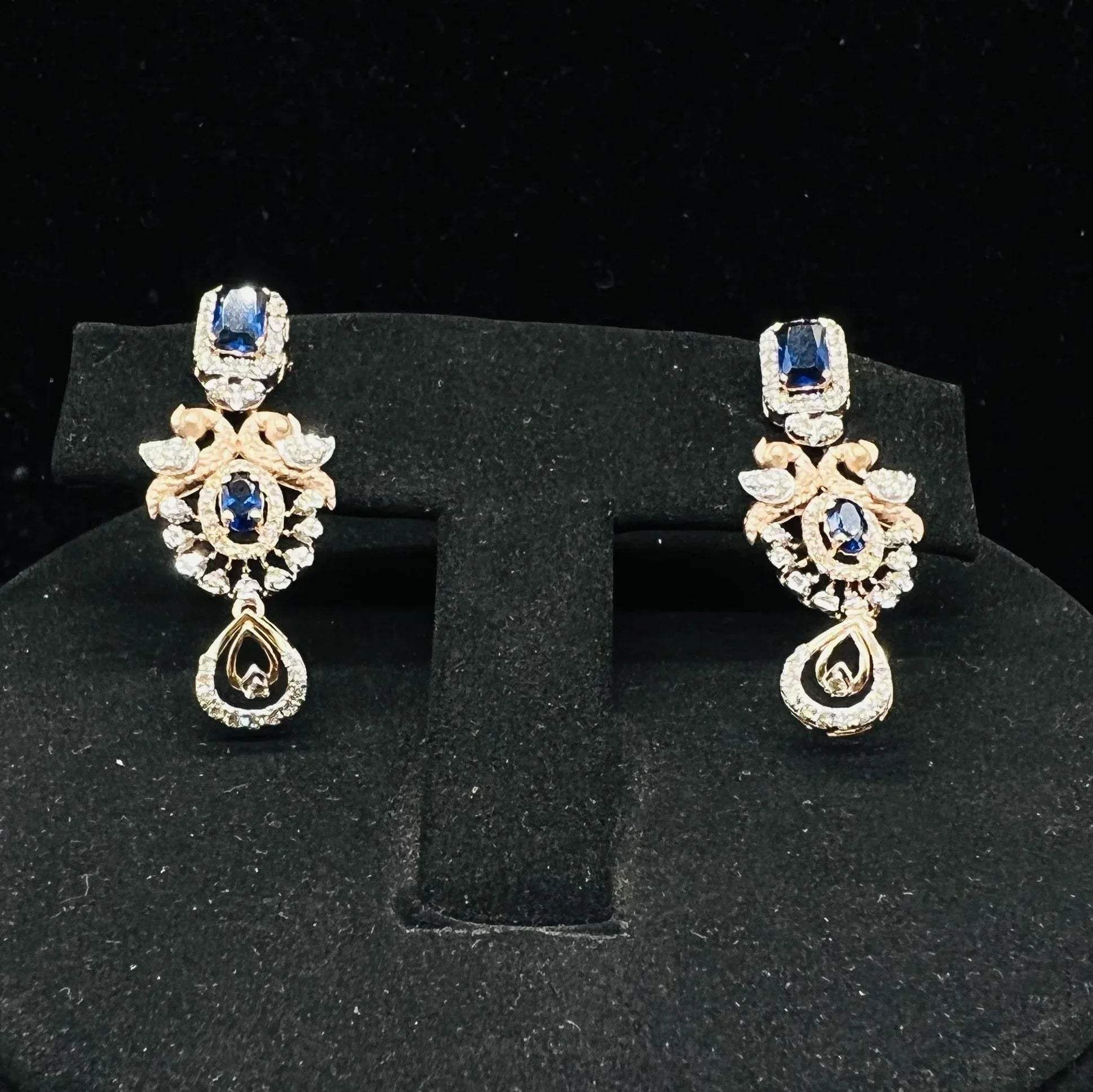 gold diamond earrings with a floral pendant, displayed on a mannequin bust.