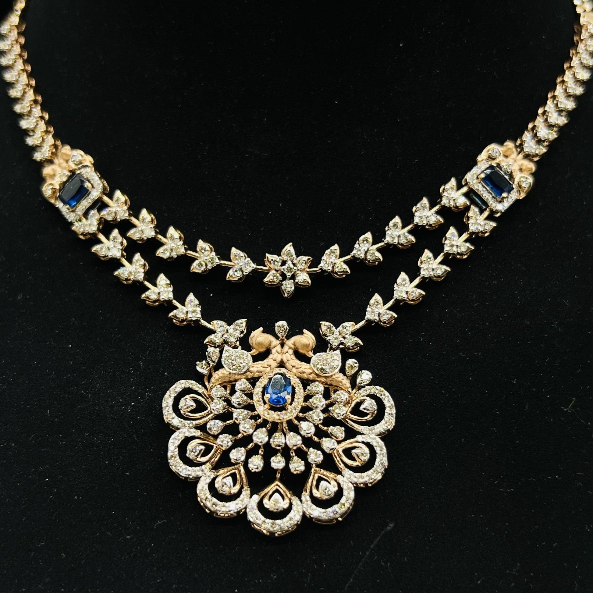 A gold diamond necklace with a floral pendant, displayed on a mannequin bust.