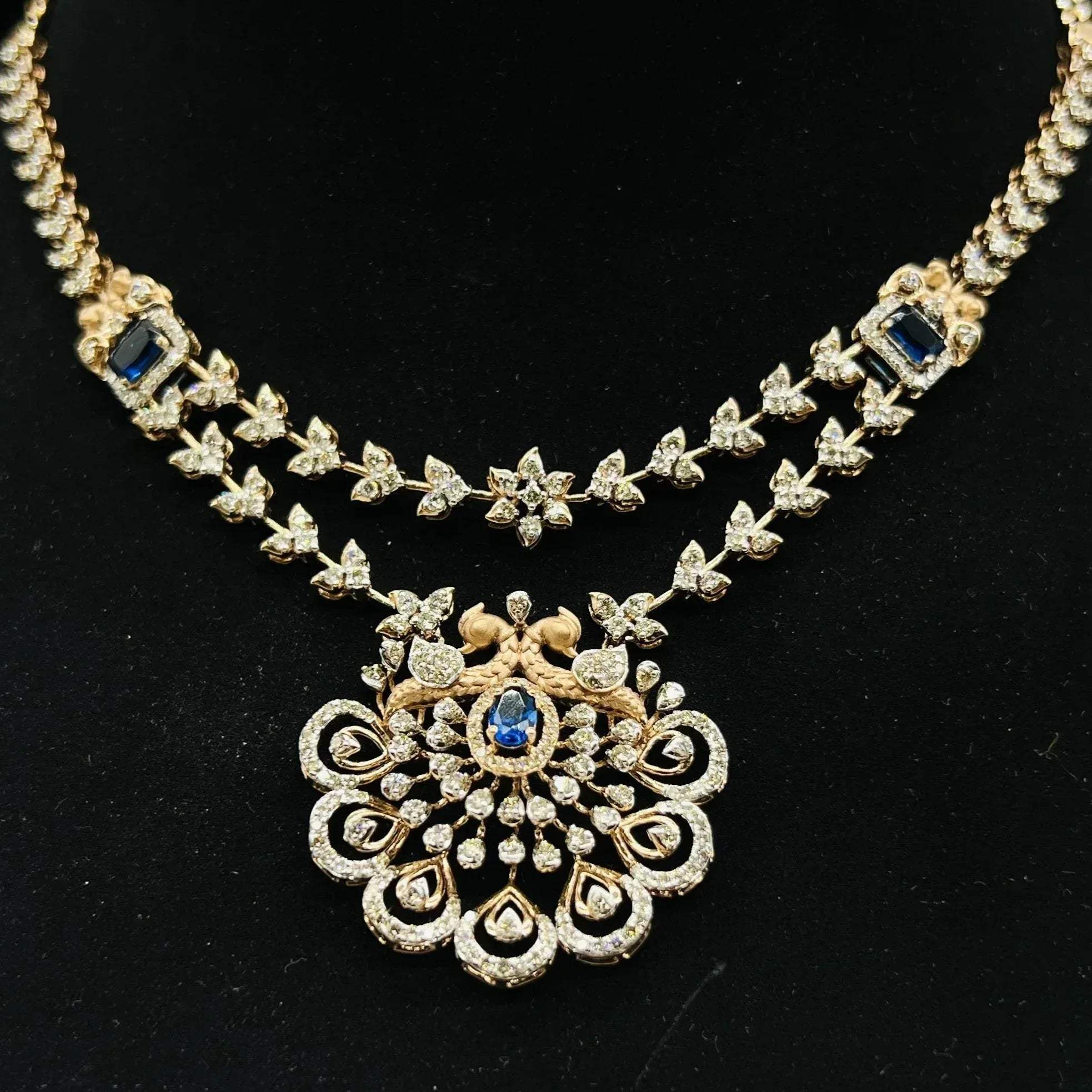 A gold diamond necklace with a floral pendant, displayed on a mannequin bust.