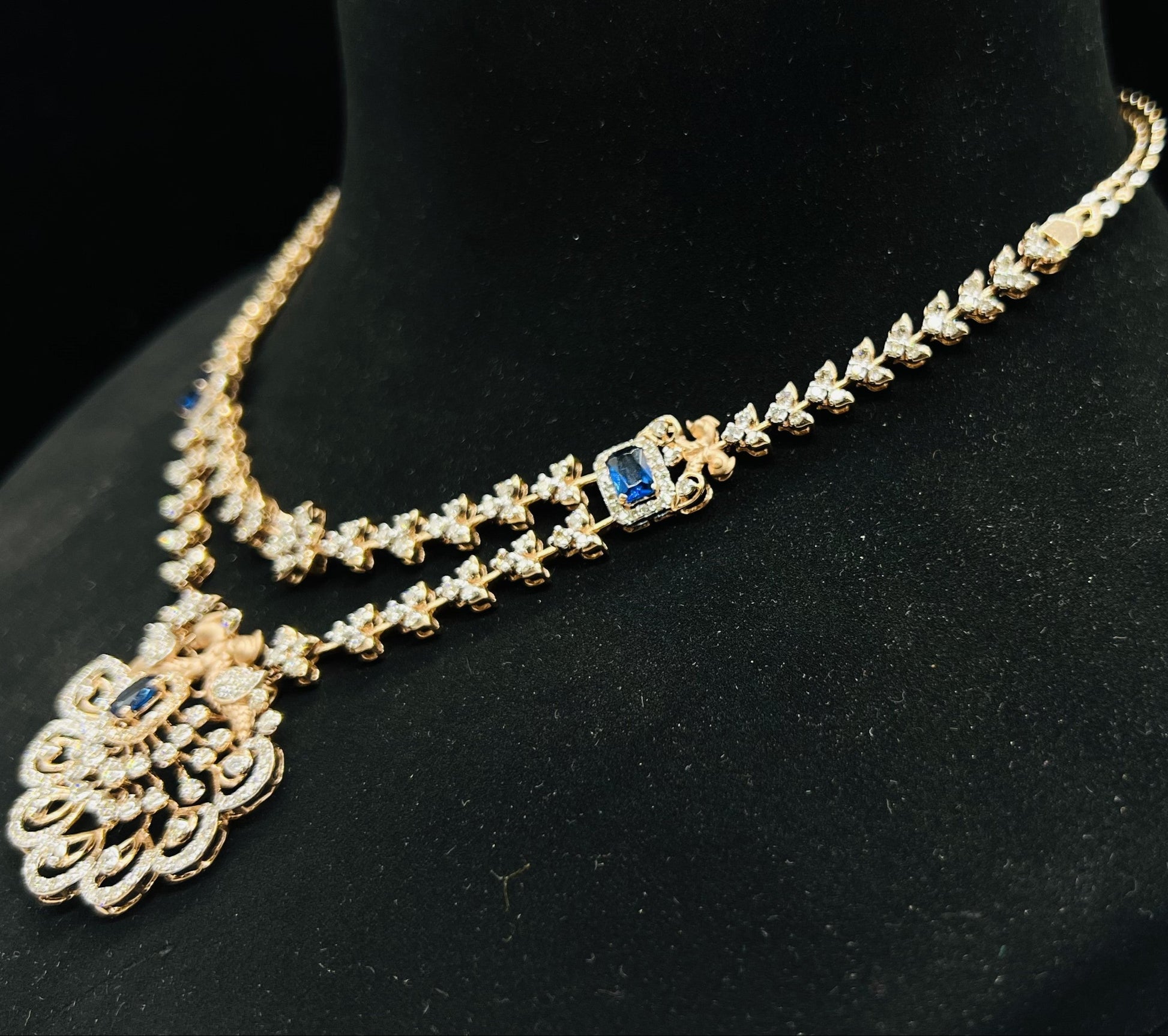 A gold diamond necklace with a floral pendant, displayed on a mannequin bust from left side.