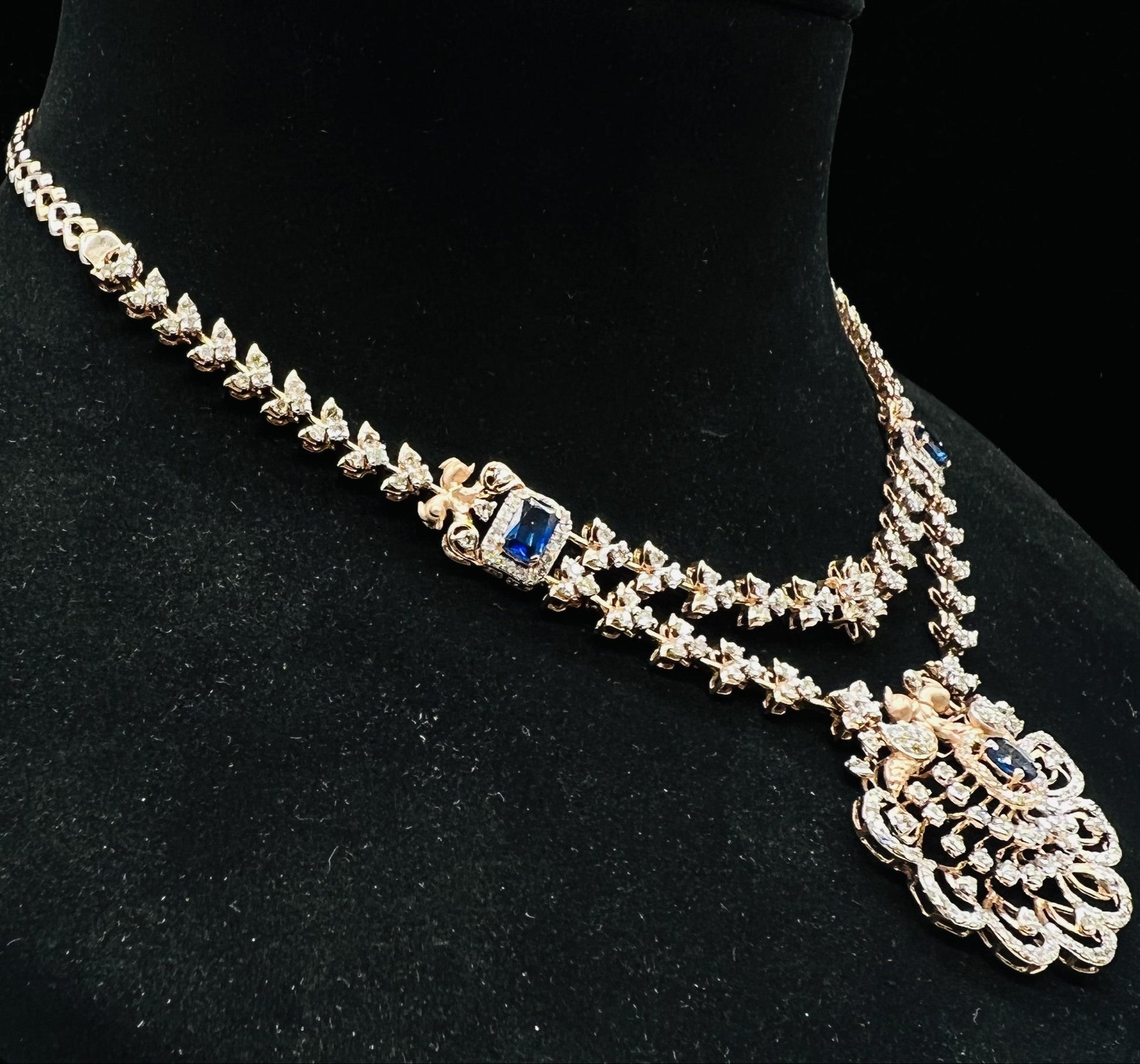 A gold diamond necklace with a floral pendant, displayed on a mannequin bust from right side.