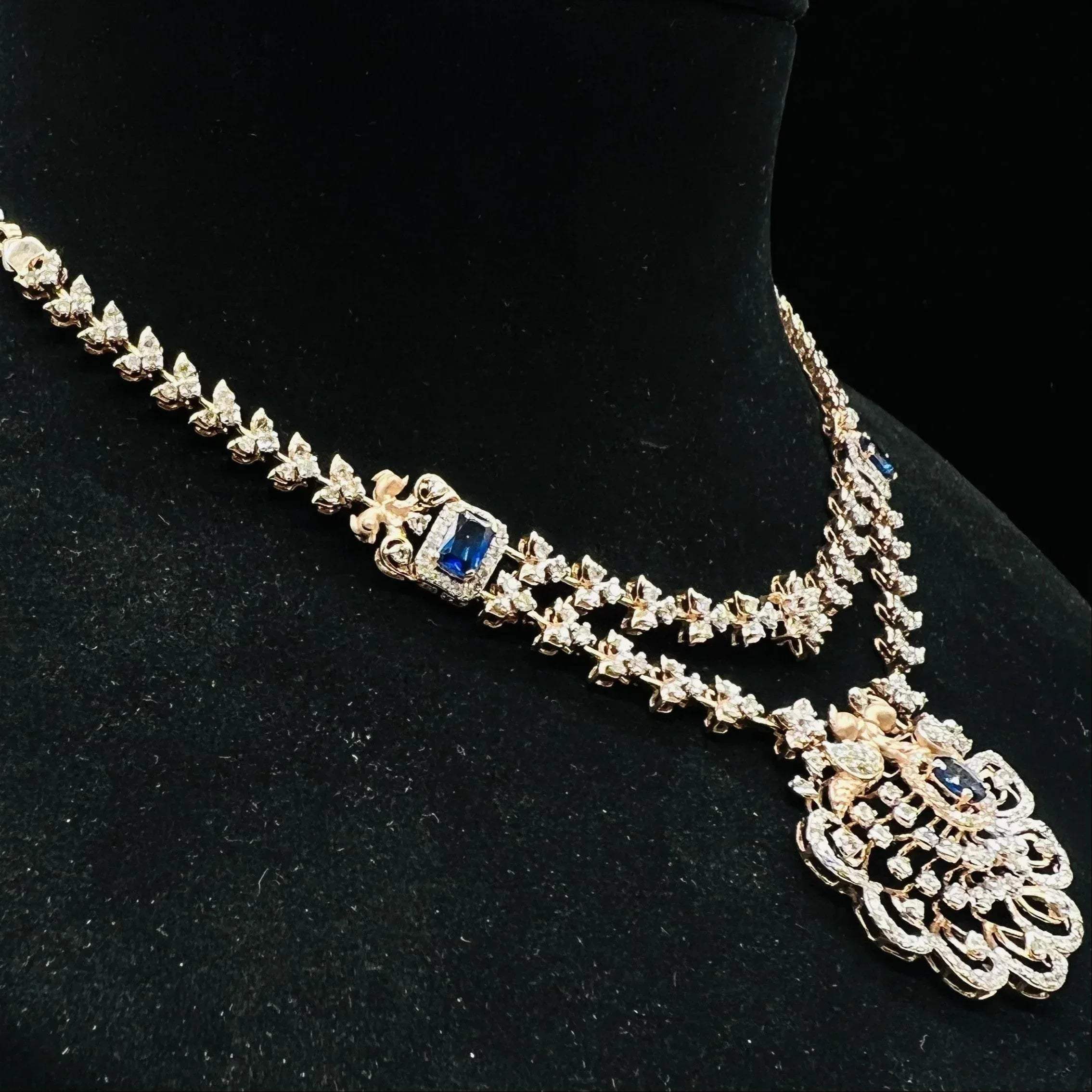 A gold diamond necklace with a floral pendant, displayed on a mannequin bust from right side.