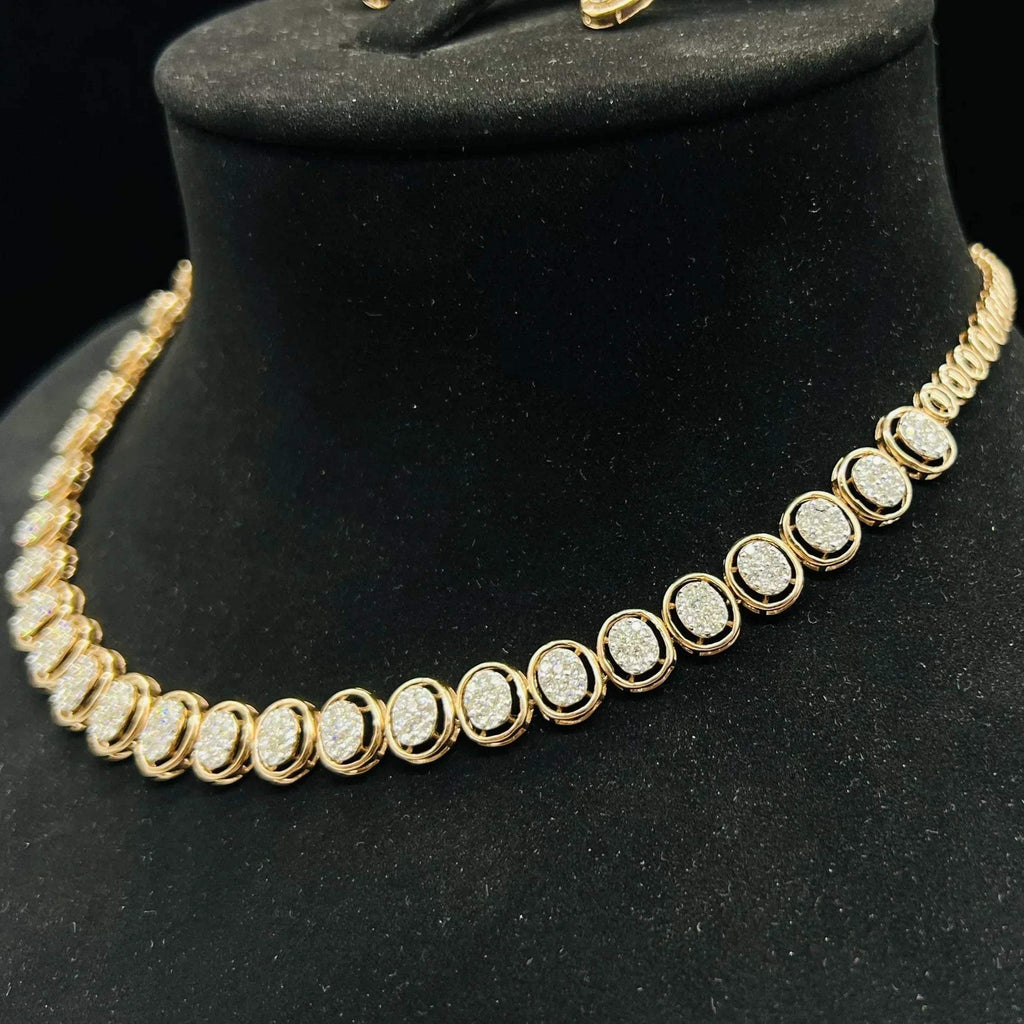 Gold diamond necklace set featuring oval-shaped, pavé-set diamonds in rose gold. The necklace has a linked design showcasing these sparkling stones evenly spaced on a black velvet background.