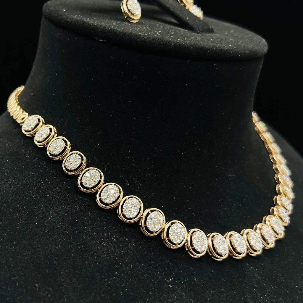 Gold diamond necklace set featuring oval-shaped, pavé-set diamonds in rose gold. The necklace has a linked design showcasing these sparkling stones evenly spaced on a black velvet background.