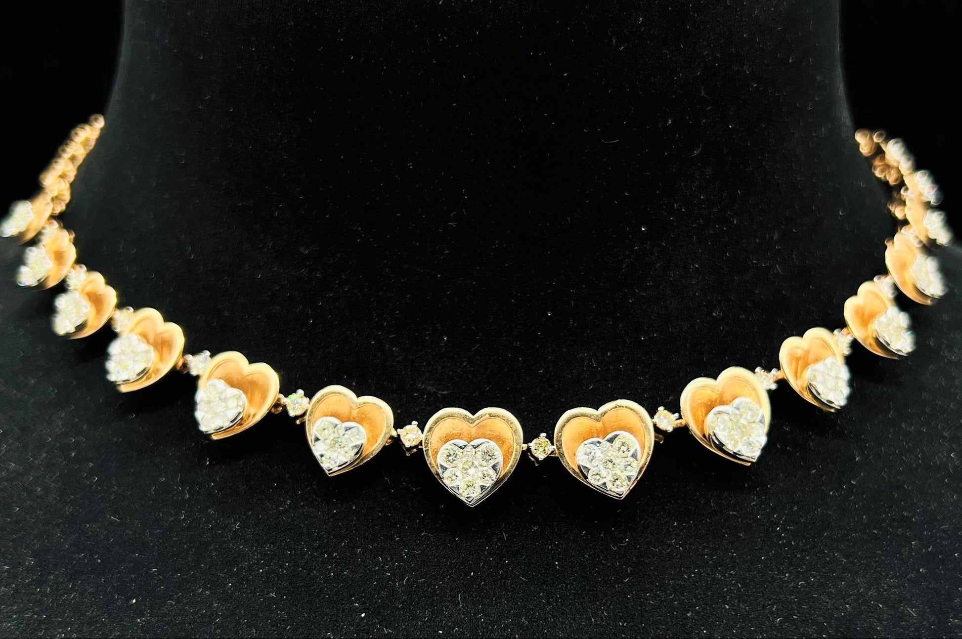 A gold necklace with round-cut diamond pendants, displayed on a black mannequin bust.