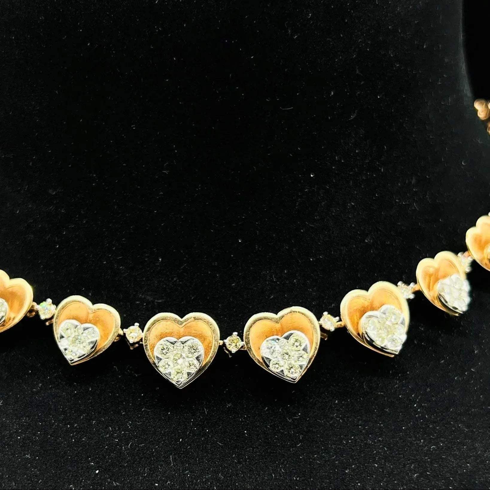 A gold necklace with round-cut diamond pendants, displayed on a black mannequin bust.