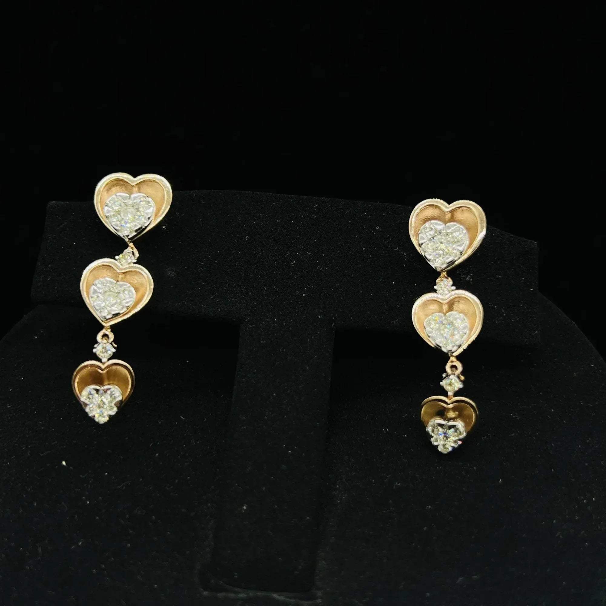 A gold earrings with round-cut diamonds and coordinating earrings, displayed on a black mannequin bust.