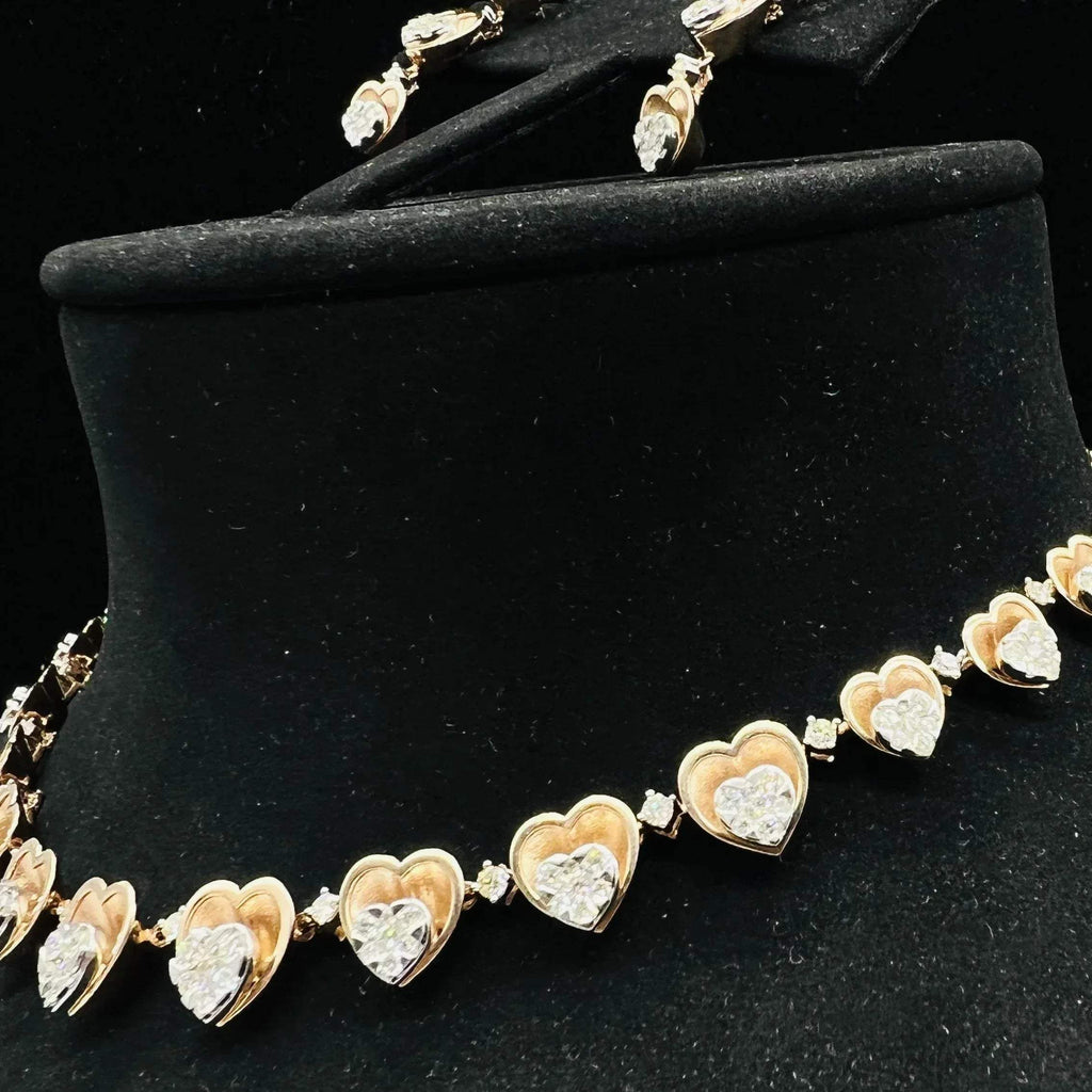 A gold necklace with round-cut diamond pendants and coordinating earrings, displayed on a black mannequin bust.