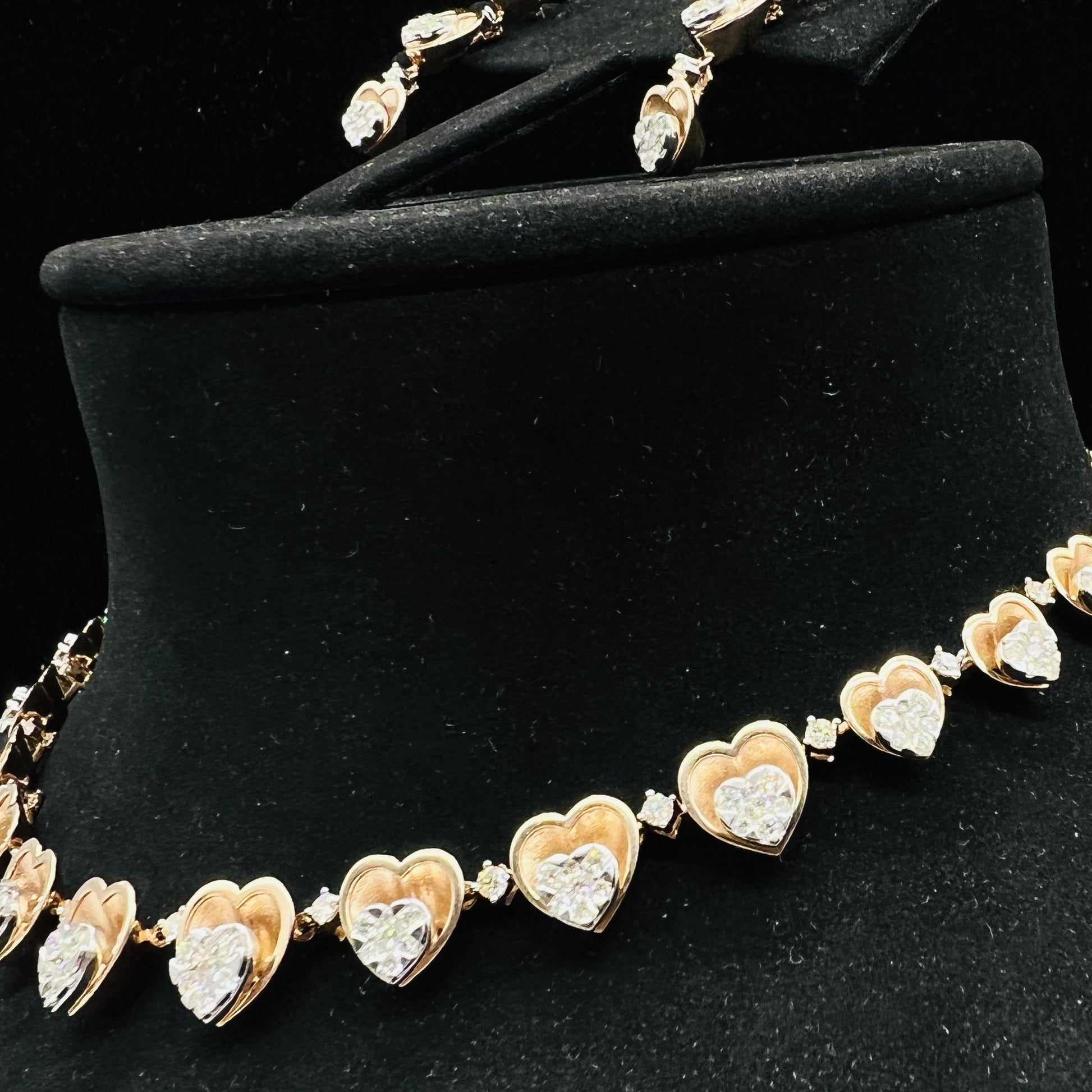 A gold necklace with round-cut diamond pendants and coordinating earrings, displayed on a black mannequin bust.